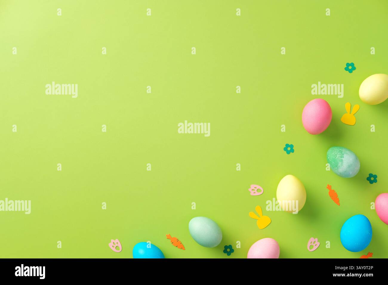 Uova di Pasqua colorate e coriandoli su sfondo verde brillante. Modello di biglietto di auguri di Pasqua Foto Stock