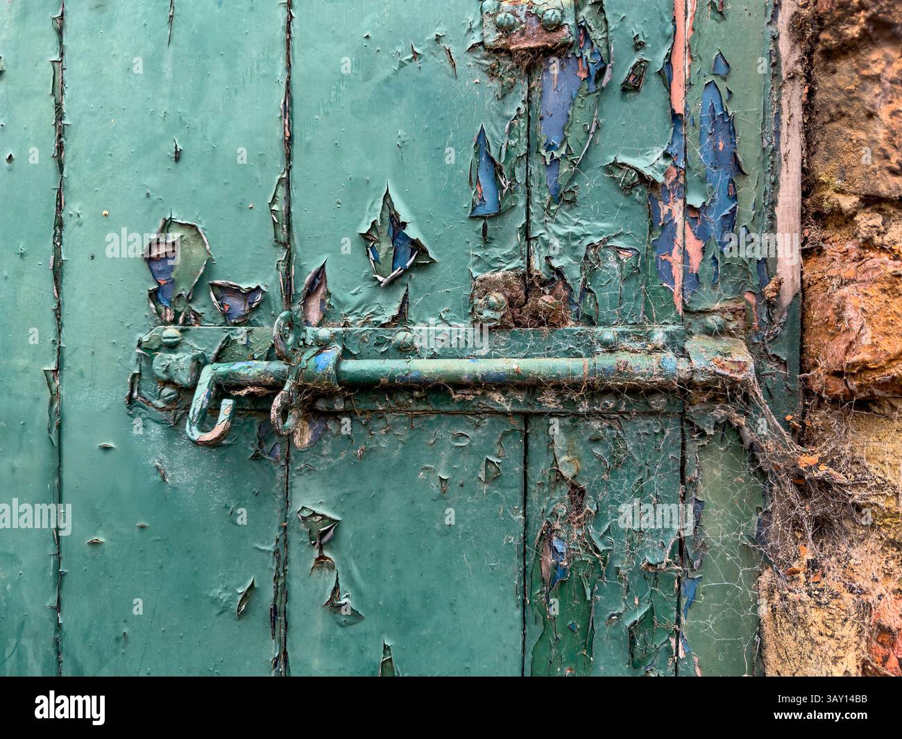 Vecchia serratura a bullone con su una porta di legno con vernice verde sbucciante Foto Stock