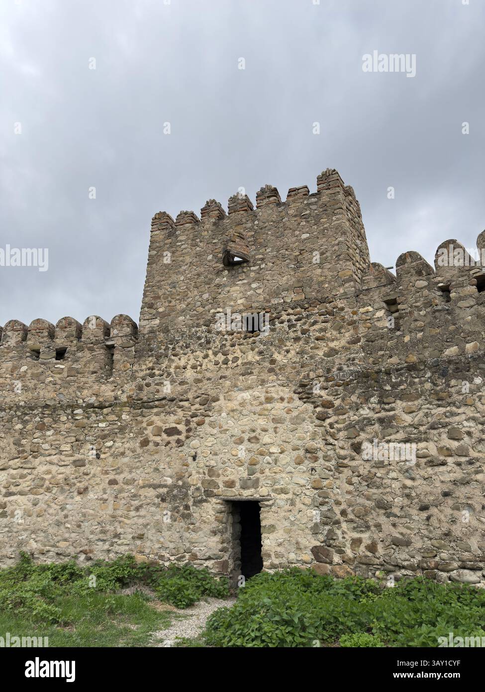 Antica fortezza in pietra con merlature contro un cielo nuvoloso, architettura storica e fortificazioni medievali. Ideale per viaggi, storia Foto Stock