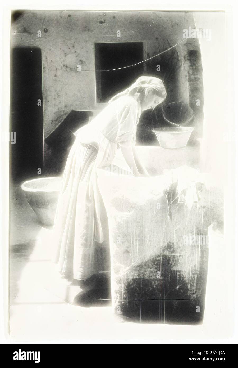 Una donna in abito d'epoca si piega su un grande lavabo in pietra, impegnata in un compito di lavaggio o pulizia, con la luce soffusa che illumina la sua espressione focalizzata su uno sfondo semplice e rustico., James W. Holcombe, inglese, attivo ca. 1890-1900, washer Girl of Capri, fine XIX secolo, stampa platino, immagine: 7 1/8 x 4 7/8 pollici (18,1 x 12,4 cm), arte classica con un tocco moderno reinventata da Artotop Foto Stock
