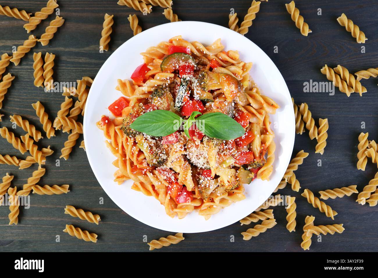 Vista dall'alto di un piatto di deliziosa pasta Fusilli in salsa di pomodoro con pasta secca sparsa intorno Foto Stock