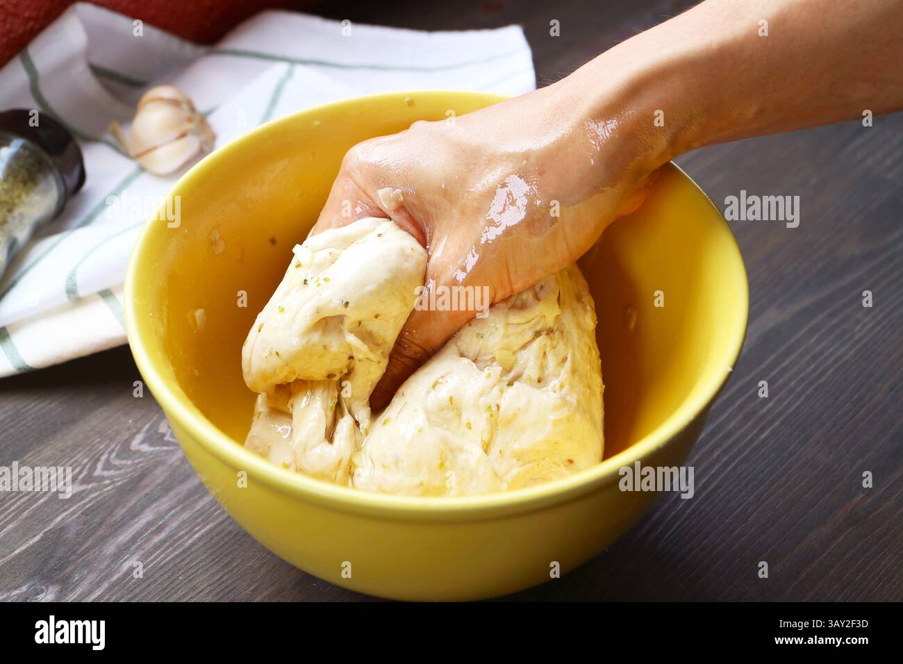 Persone che impastano l'impasto italiano mescolato con le erbe in un recipiente per mescolare Foto Stock