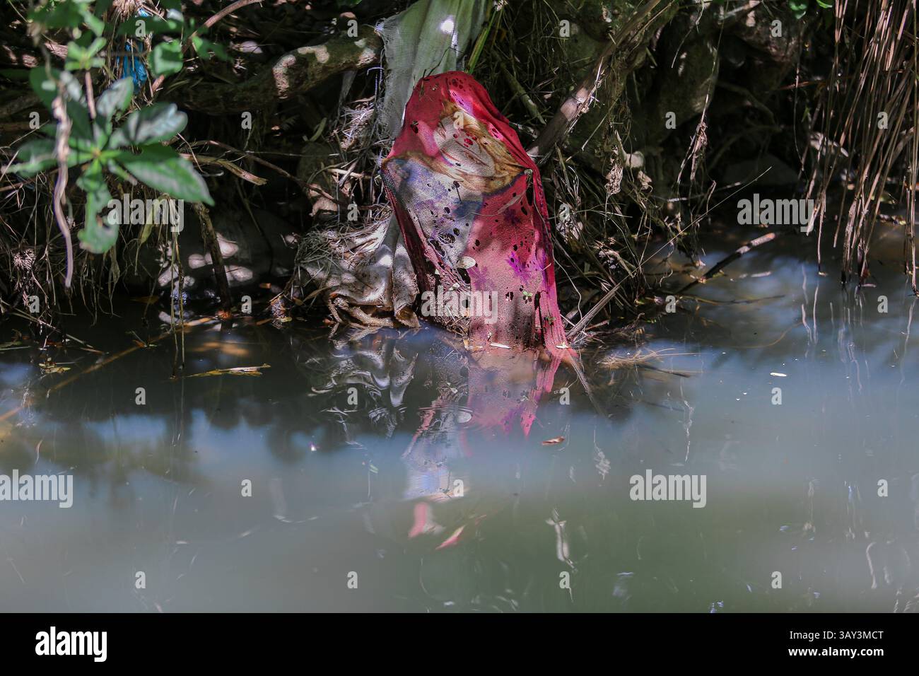 Provincia di Quezon, Filippine. 22 aprile 2025. Il tessuto stampato congelato gettato nel fiume riappare durante la stagione secca vicino a un deposito illegale in un letto del fiume. Quando la magia Disney scompare, trasformandosi in rifiuti inquinanti per l'ambiente. Con il calo del livello dell'acqua, questi discarici temporanei crescono nel tempo, con i residenti del villaggio e le comunità vicine che scartano i rifiuti direttamente nel fiume, supponendo che la stagione delle piogge possa lavare via tutto. Il dumping illegale è un problema ricorrente nell'arcipelago filippino, che è tra i maggiori inquinatori oceanici del mondo. Crediti: Kevin Izorce/Alamy Live News Foto Stock