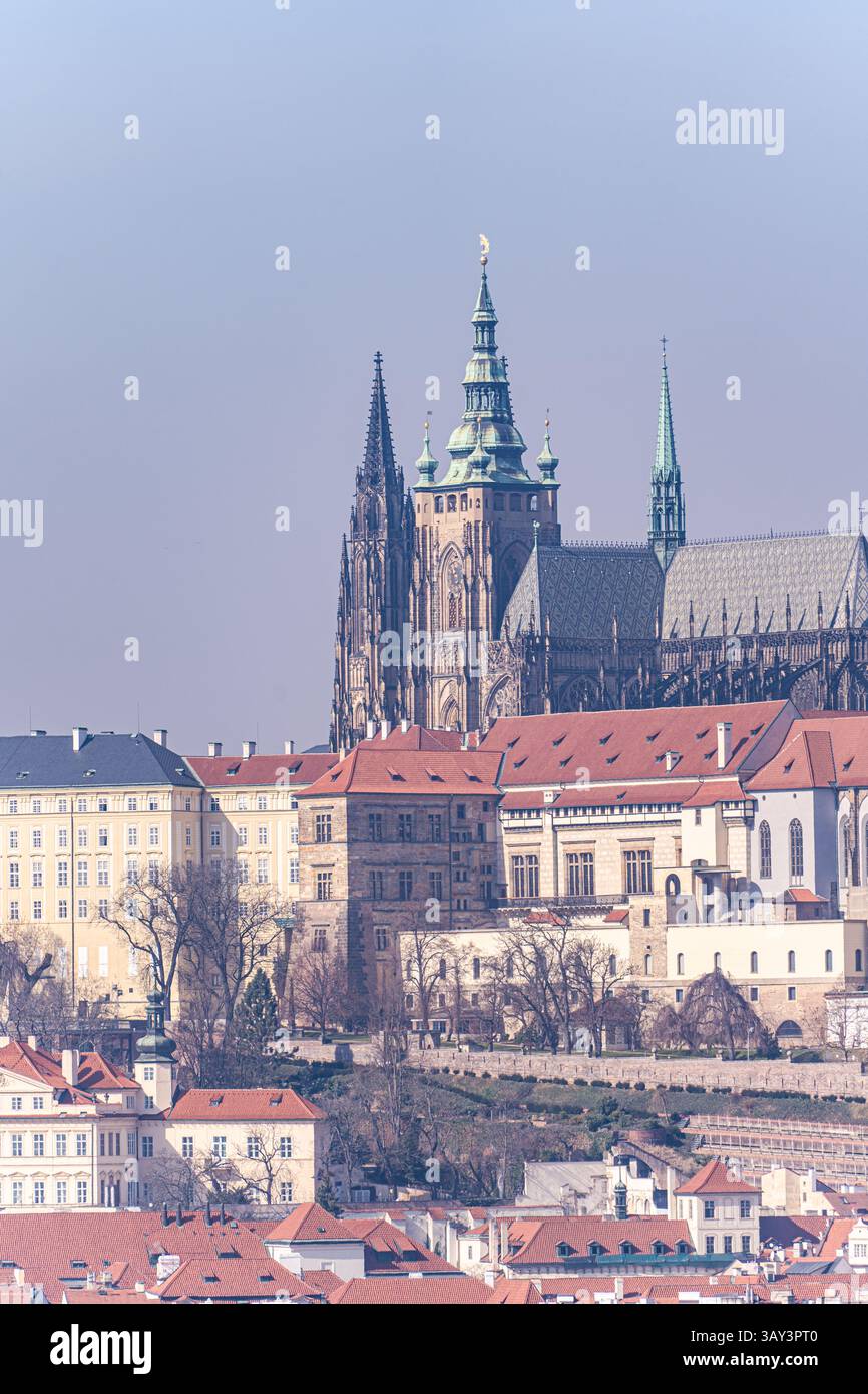 Questa immagine cattura la maestosa cattedrale di San Vito che torreggia sopra l'architettura storica di Praga con un filtro vintage da sogno. Foto Stock