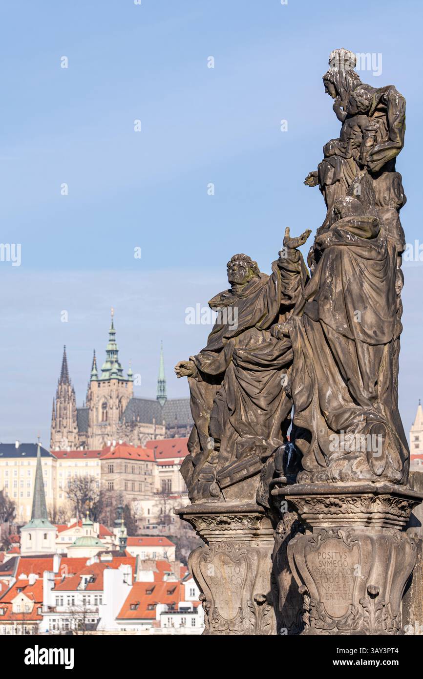 Figure storiche scolpite spiccano con l'iconico castello di Praga che si estende in lontananza, catturato sotto il cielo limpido a metà strada attraverso la d.C. Foto Stock