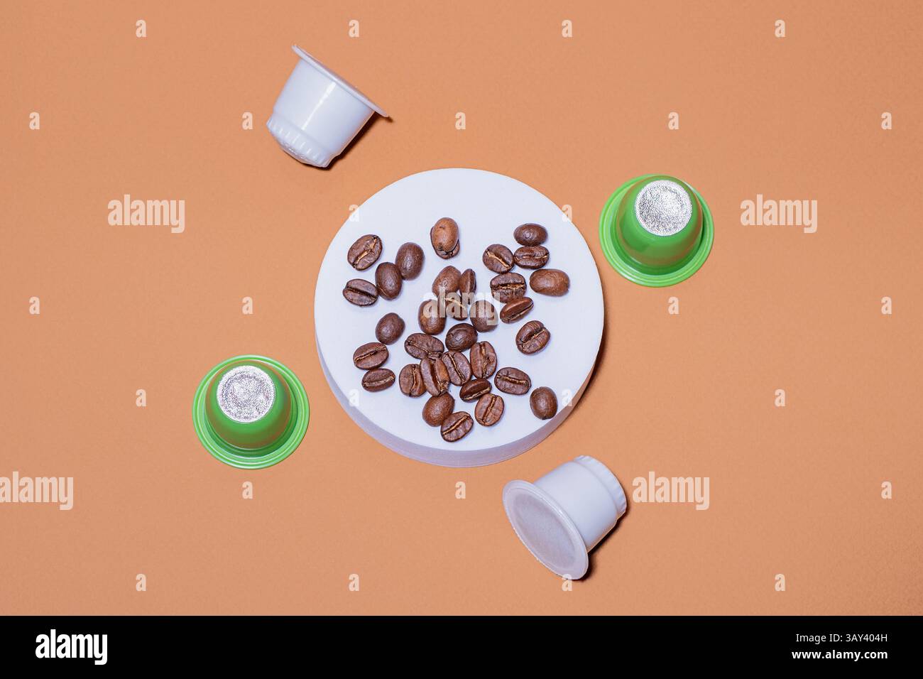 Chicchi di caffè biodegradabili e cialde ecologiche disposte in modo creativo su uno sfondo di pesca, sottolineando la sostenibilità e la cultura del caffè moderna con un Foto Stock