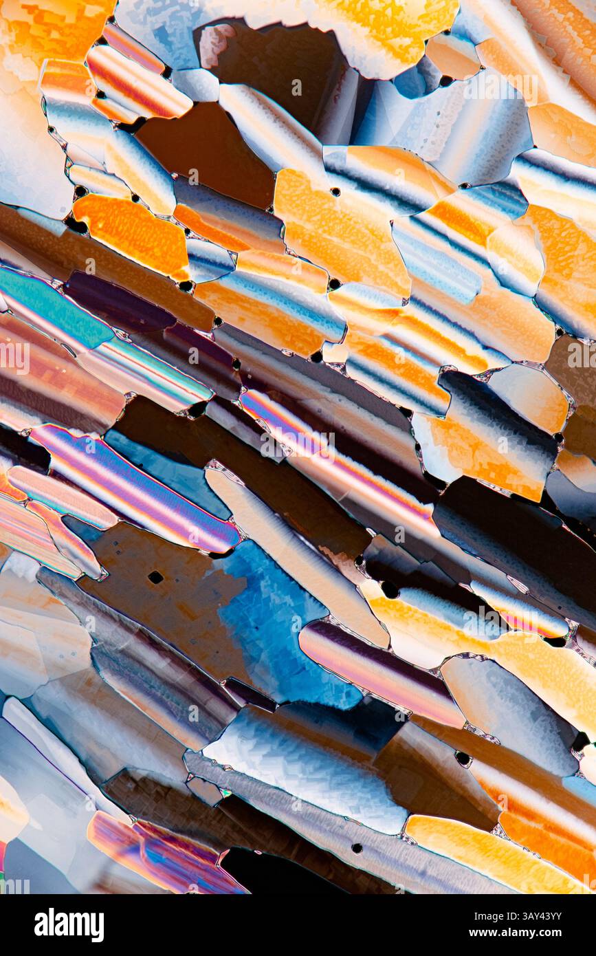 Una vista microscopica colorata dei cristalli liquidi con una gamma di arance vivaci, blu e sfumature riflettenti. Foto Stock