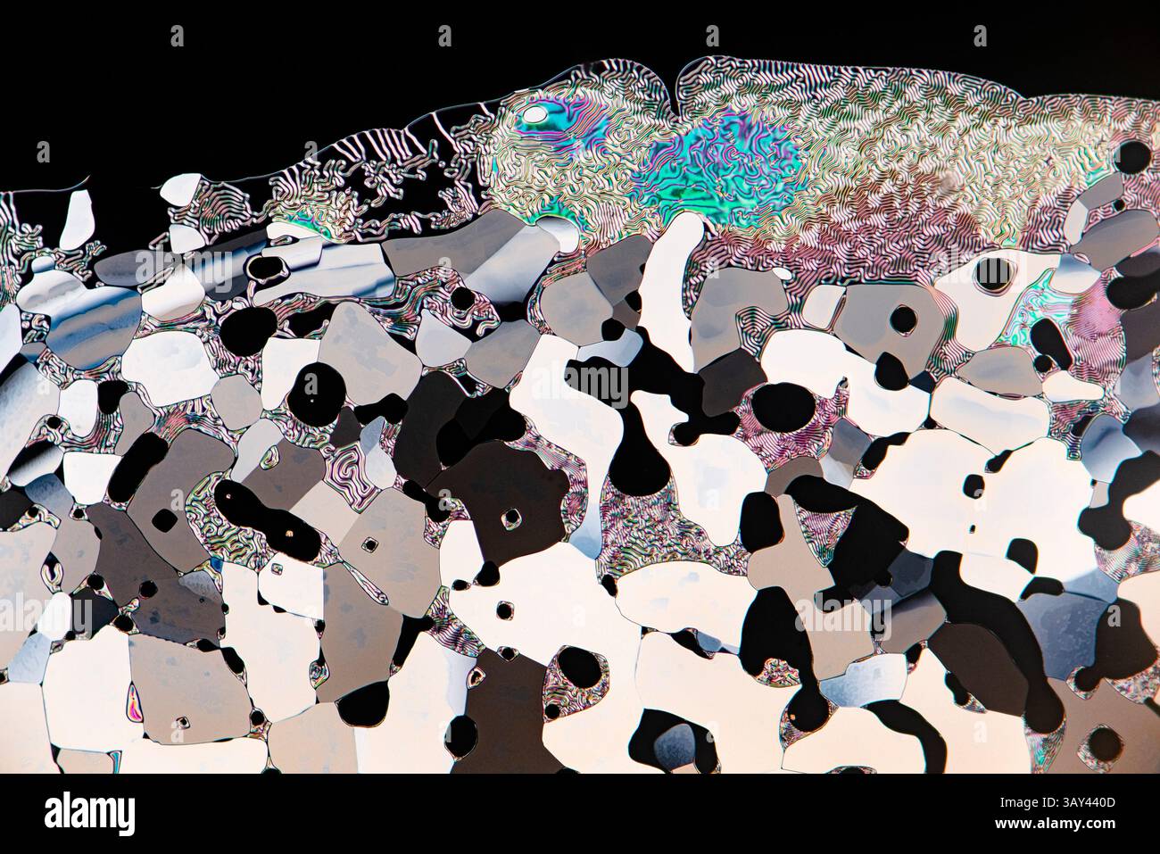 Un colorato display di cristalli liquidi sotto un microscopio, che mostra una tavolozza di colori vivaci blu, verdi, rosa e sezioni monocromatiche. Foto Stock