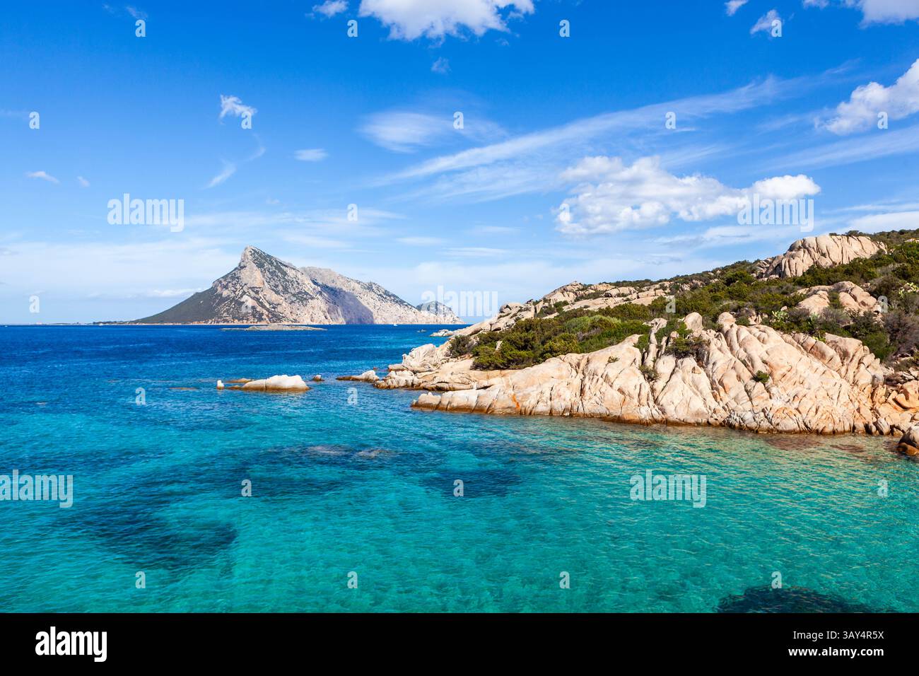 Le acque turchesi incontrano le coste rocciose in Sardegna, Italia. L'isola di Tavolara sorge in lontananza, una perfetta vista delle vacanze. Costa di smeraldo. Foto Stock
