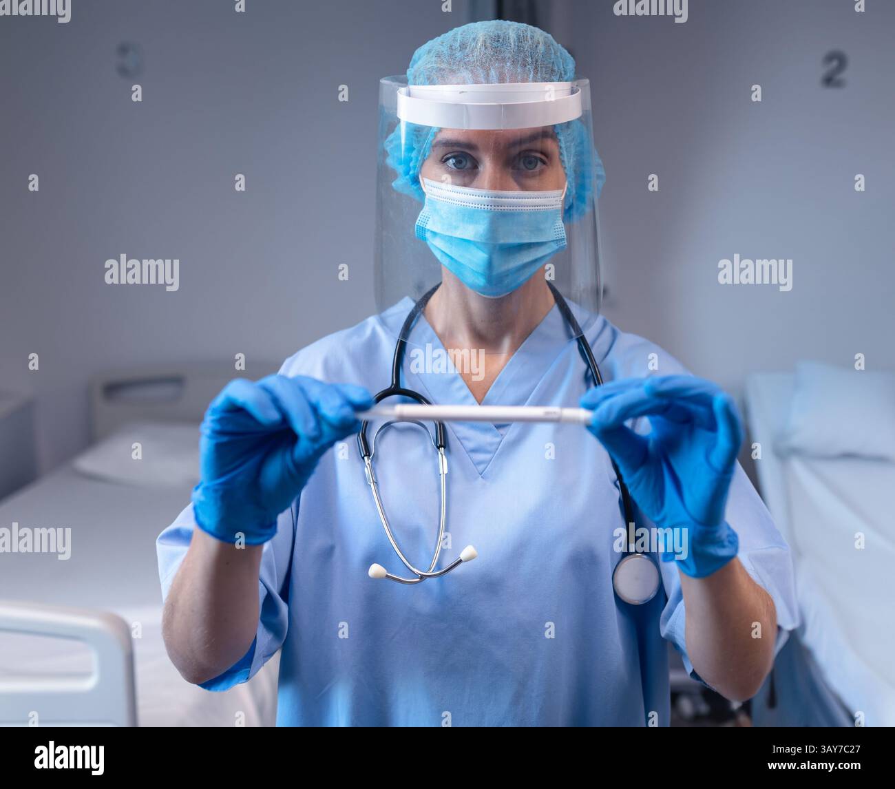 Infermiere che tiene il tampone nasale in reparto ospedaliero, con stetoscopio intorno al collo e guanti Foto Stock