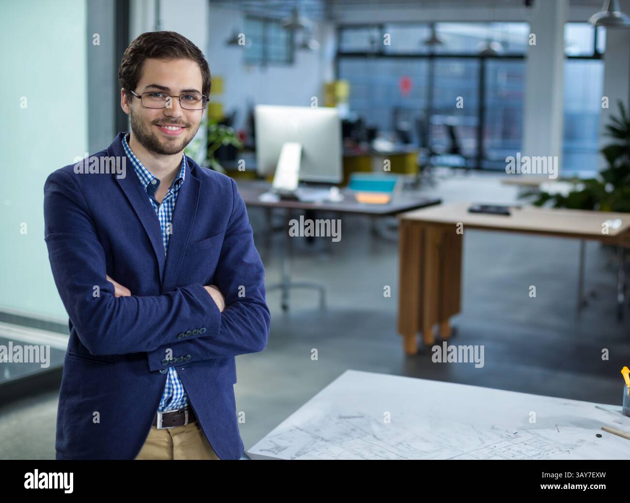 uomo alla fine dei vent'anni che esamina i progetti in un ufficio open space con grandi finestre, spazio per le copie Foto Stock