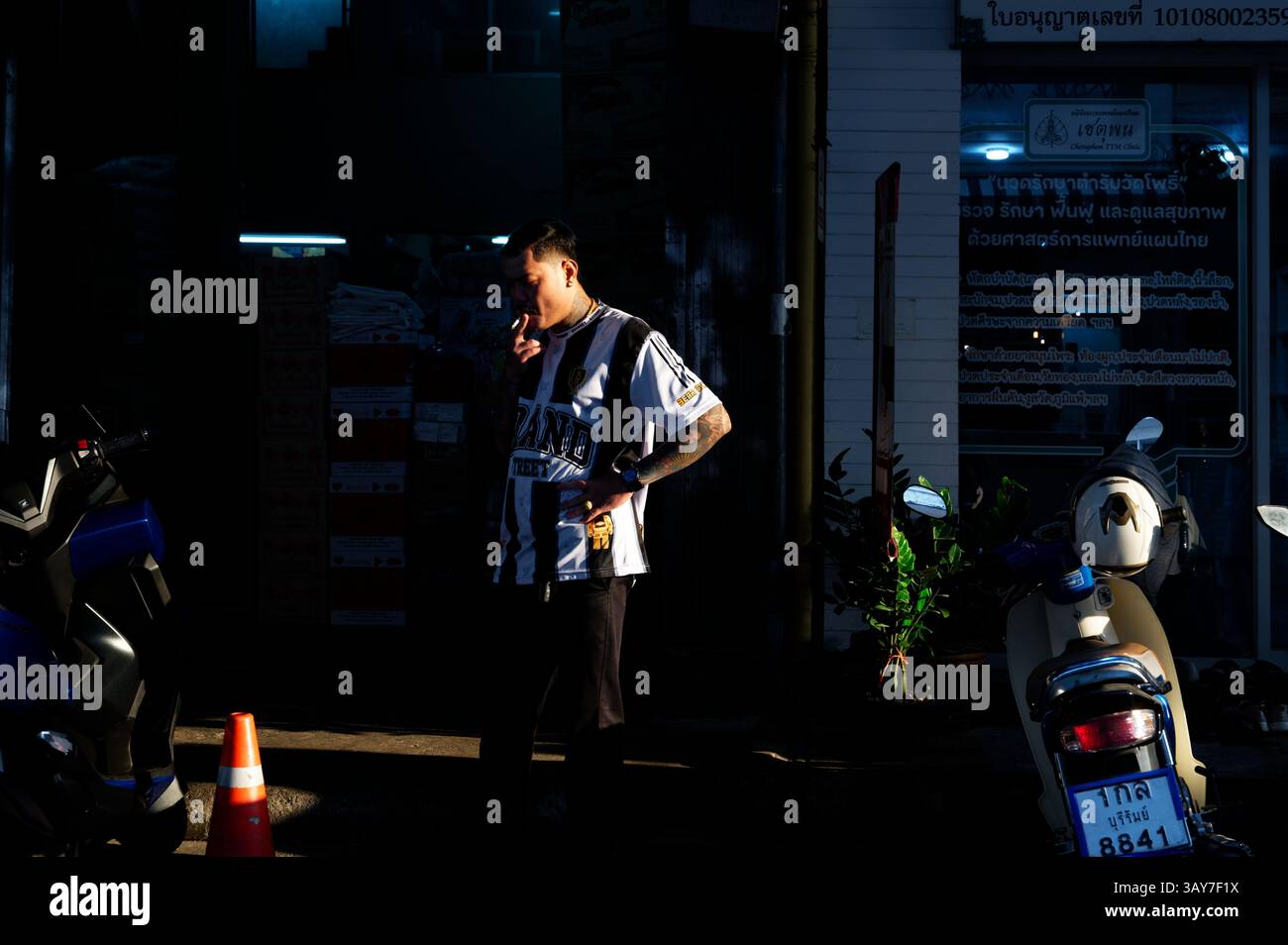 L'uomo si trova in una spettacolare luce serale fuori da un negozio nel centro di Bangkok Foto Stock