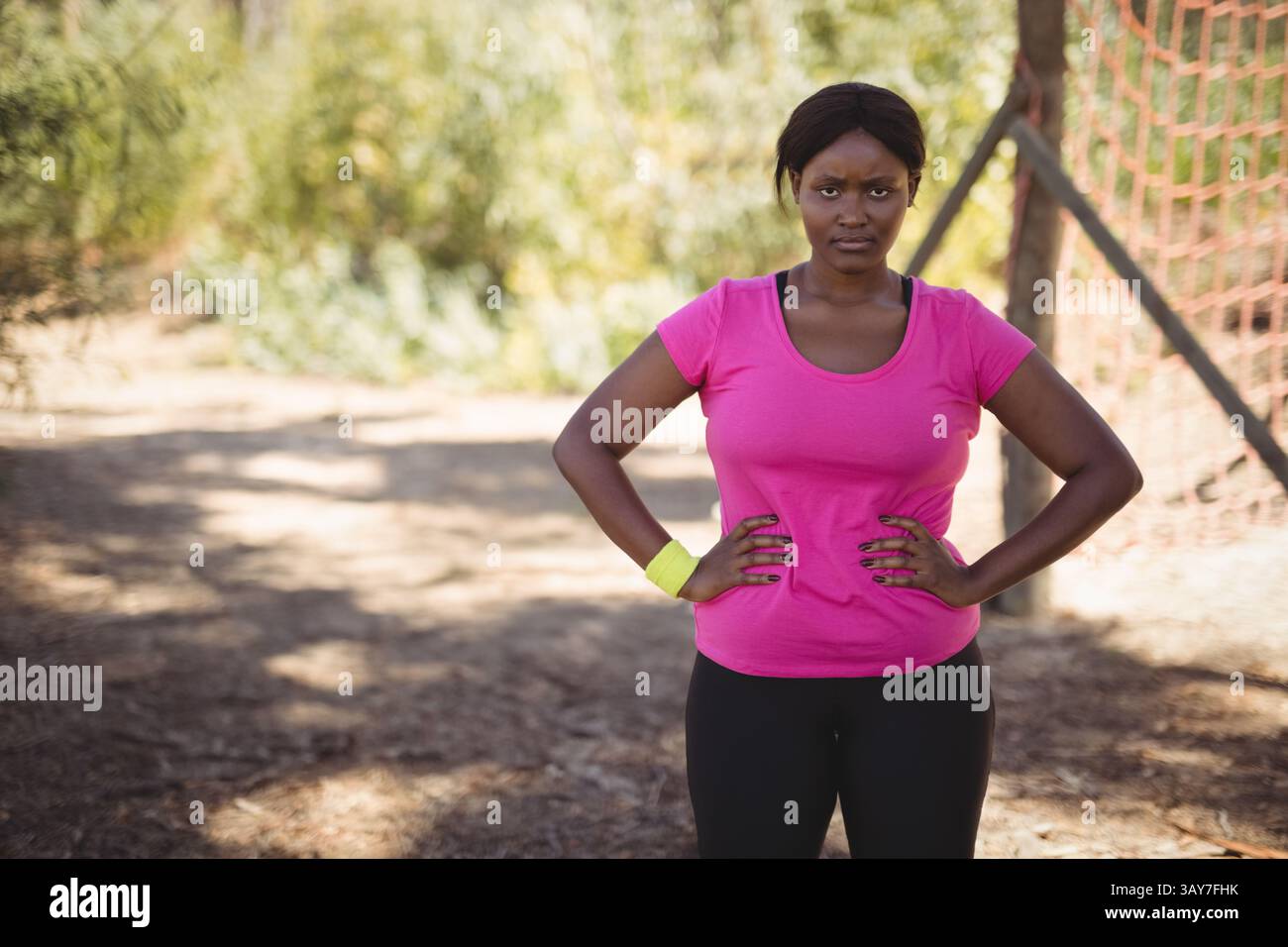 Giovane donna afroamericana che posa con le mani sui fianchi sul campo sterrato, con rete da calcio rossa Foto Stock