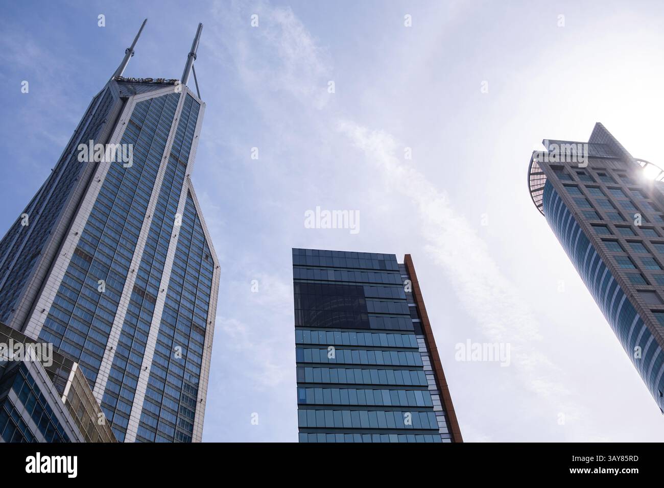 Edifici cittadini contro il cielo nuvoloso blu, grattacieli alti per uffici con vista ad angolo basso Foto Stock