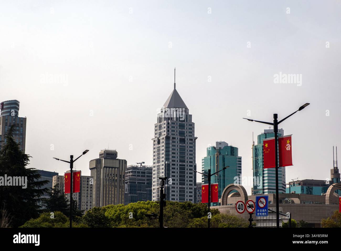 Cina, centro città di Shanghai. Alti edifici, bandiere cinesi sui lampioni stradali e segnali stradali Foto Stock