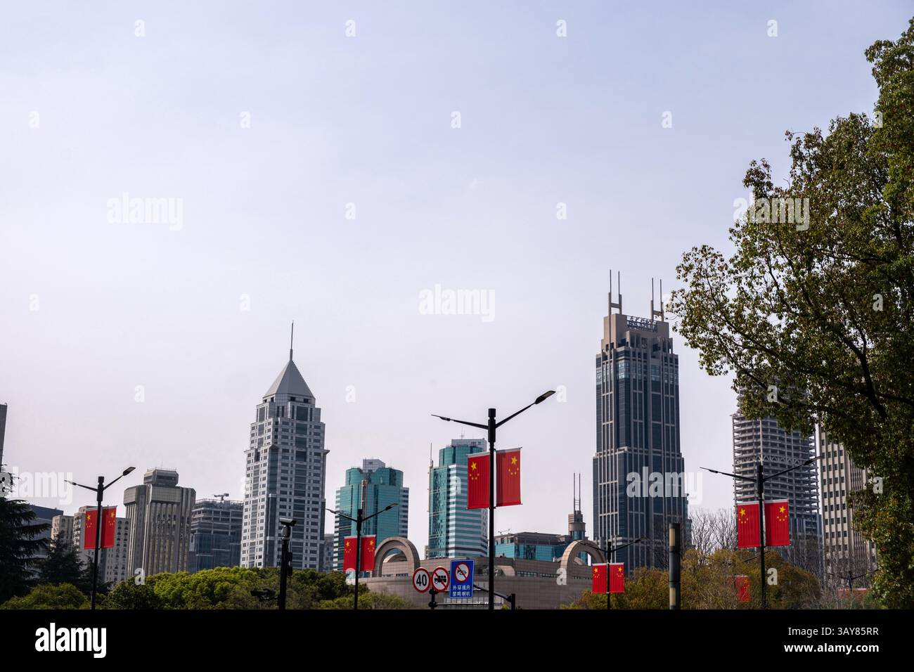 Cina, centro città di Shanghai. Alti edifici, bandiere cinesi sui lampioni stradali e segnali stradali Foto Stock