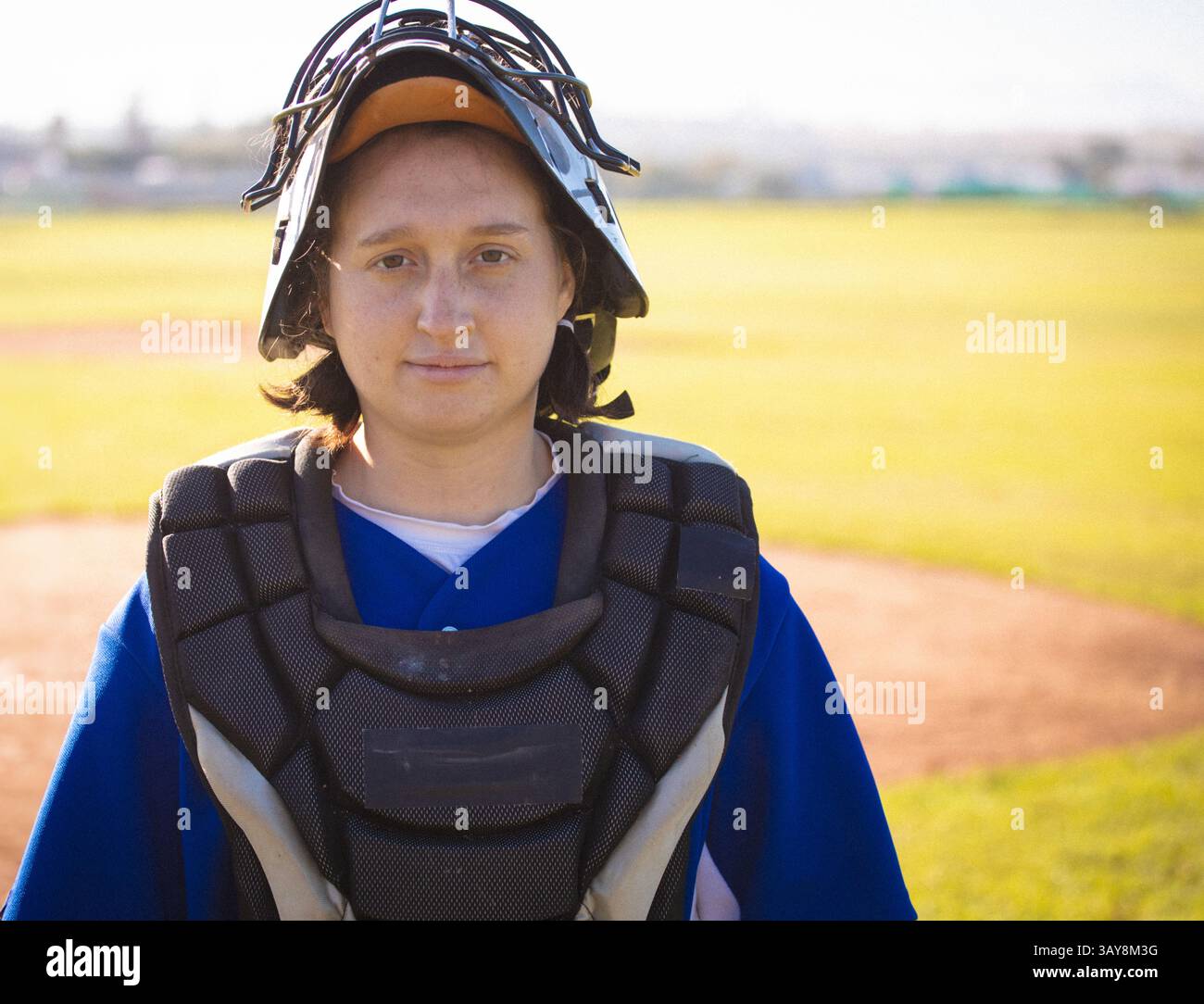 donna bi-razziale in piedi su terra rossa con casco da ricevitore e protezione del petto Foto Stock
