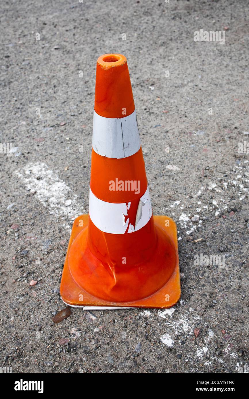 I coni segnaletici arancioni rappresentano un segnale di avvertenza sulla strada asfaltata, che indica i lavori di costruzione e richiede attenzione per la sicurezza Foto Stock