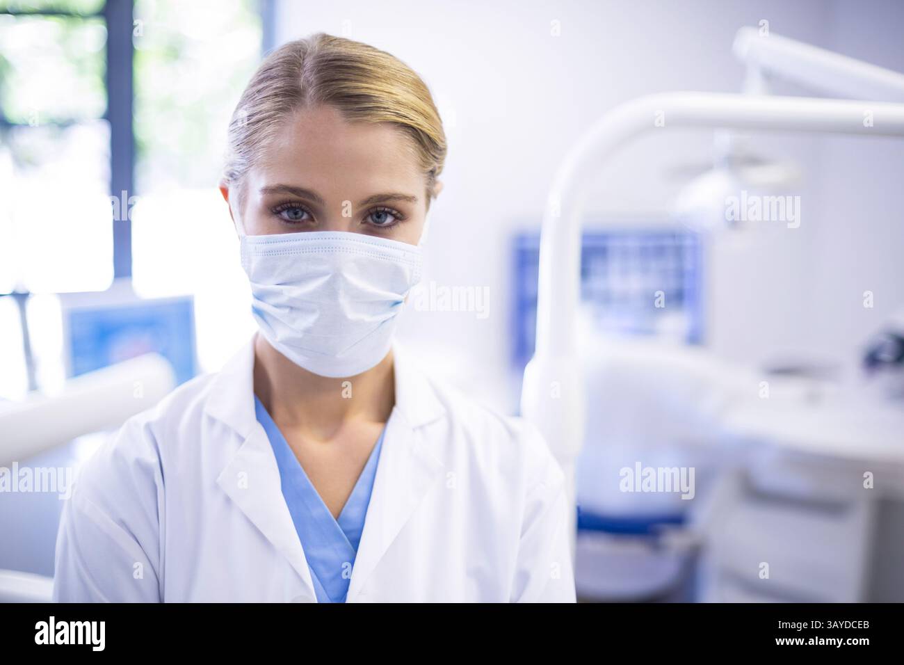 Dentista donna in piedi nella moderna sala di trattamento dentale, con lampada, sedia dentale, monitor a raggi X. Foto Stock