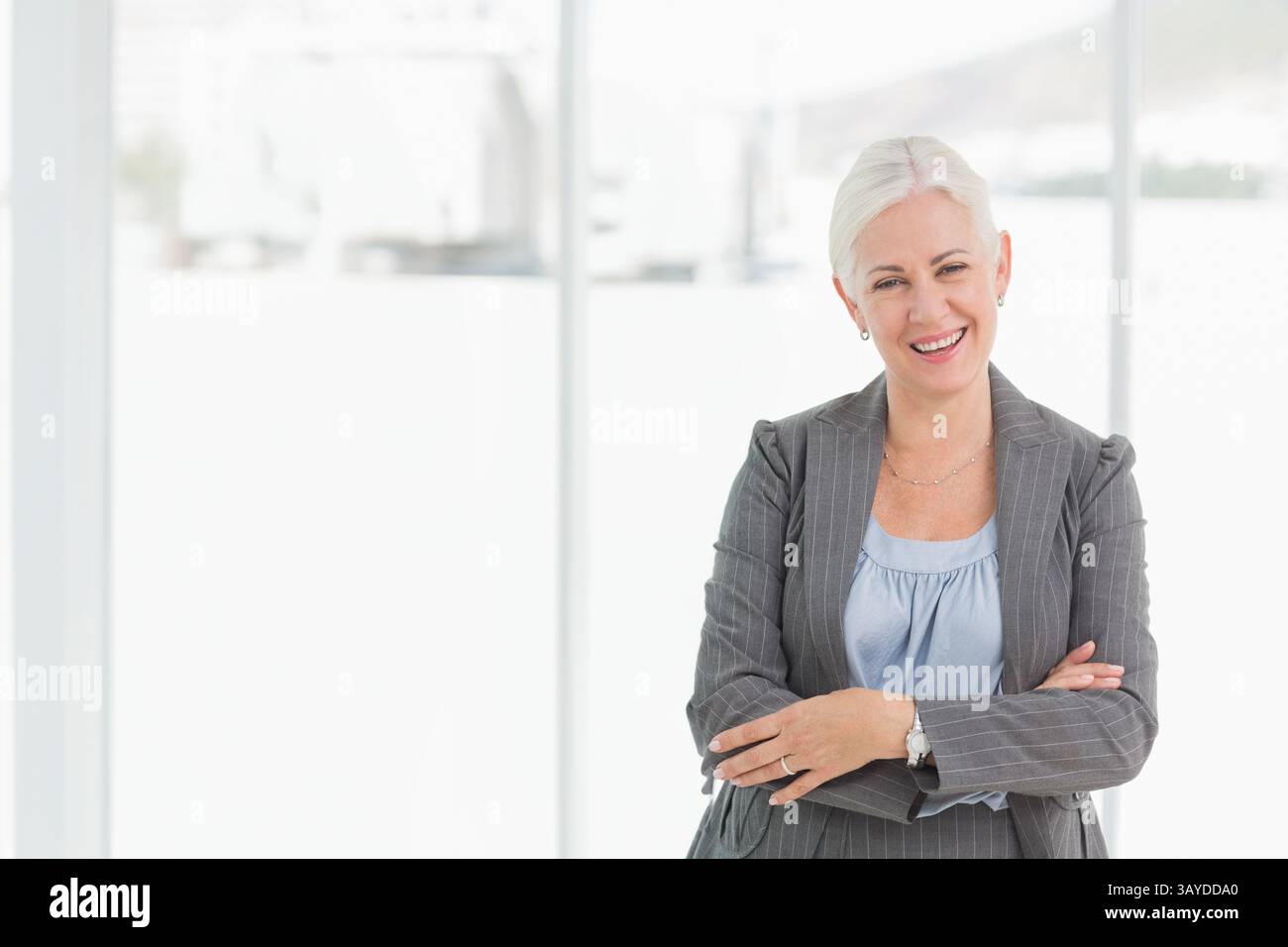 Donna di mezza età professionale in piedi in ufficio con un blazer pinstripe, spazio di copia Foto Stock