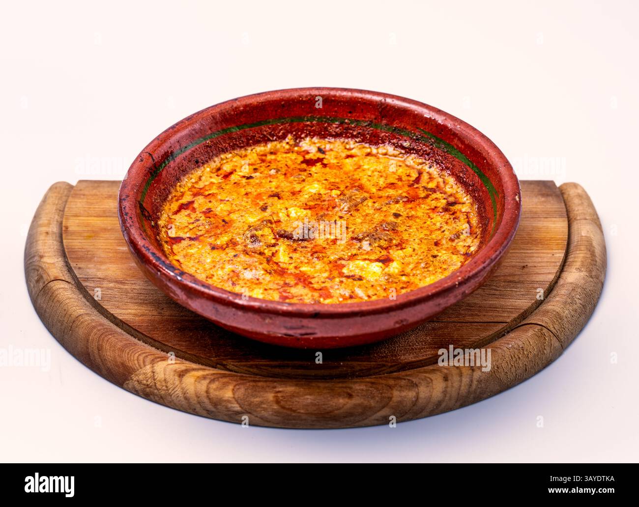 Un rustico Tavë Dheu che trasuda un profondo patrimonio culinario albanese, presentato su una tavola di legno intemprata in una tradizionale pentola di argilla Foto Stock