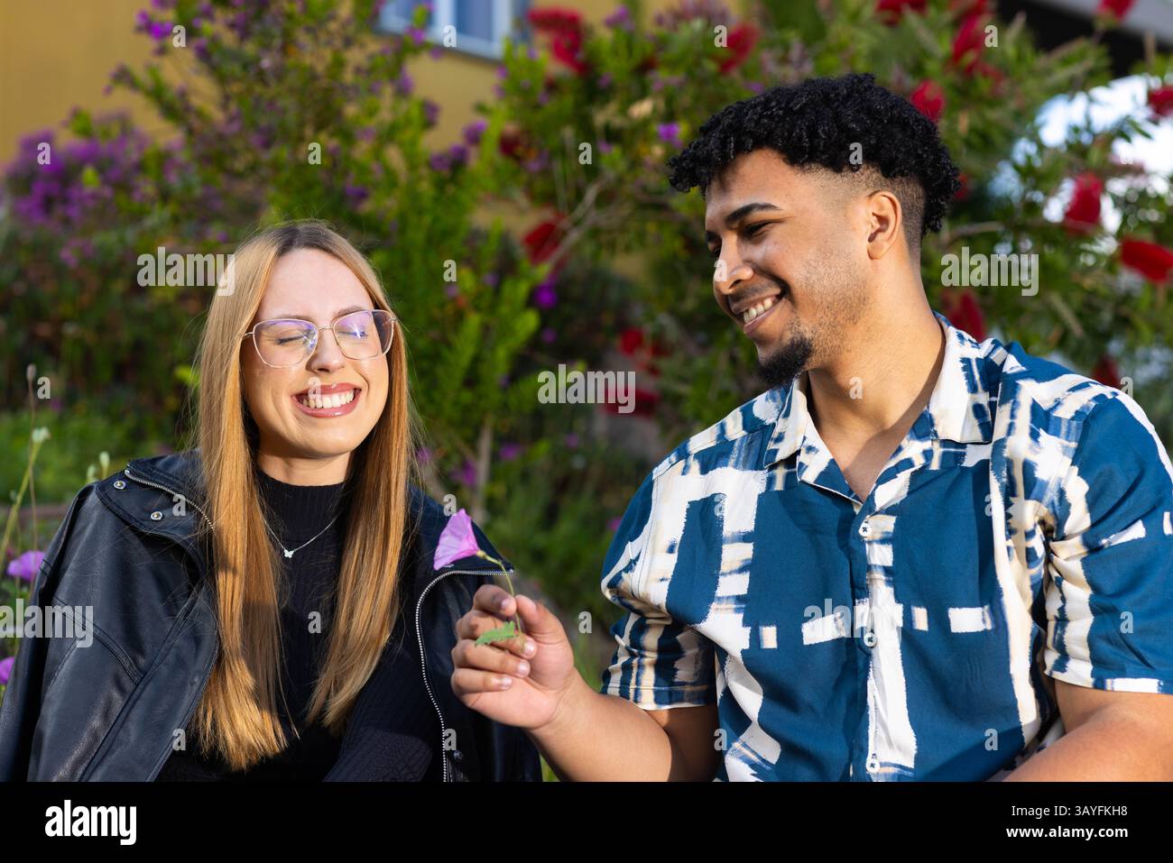 Momenti di gioia condivisi tra amici che donano fiori nel giardino fiorito Foto Stock