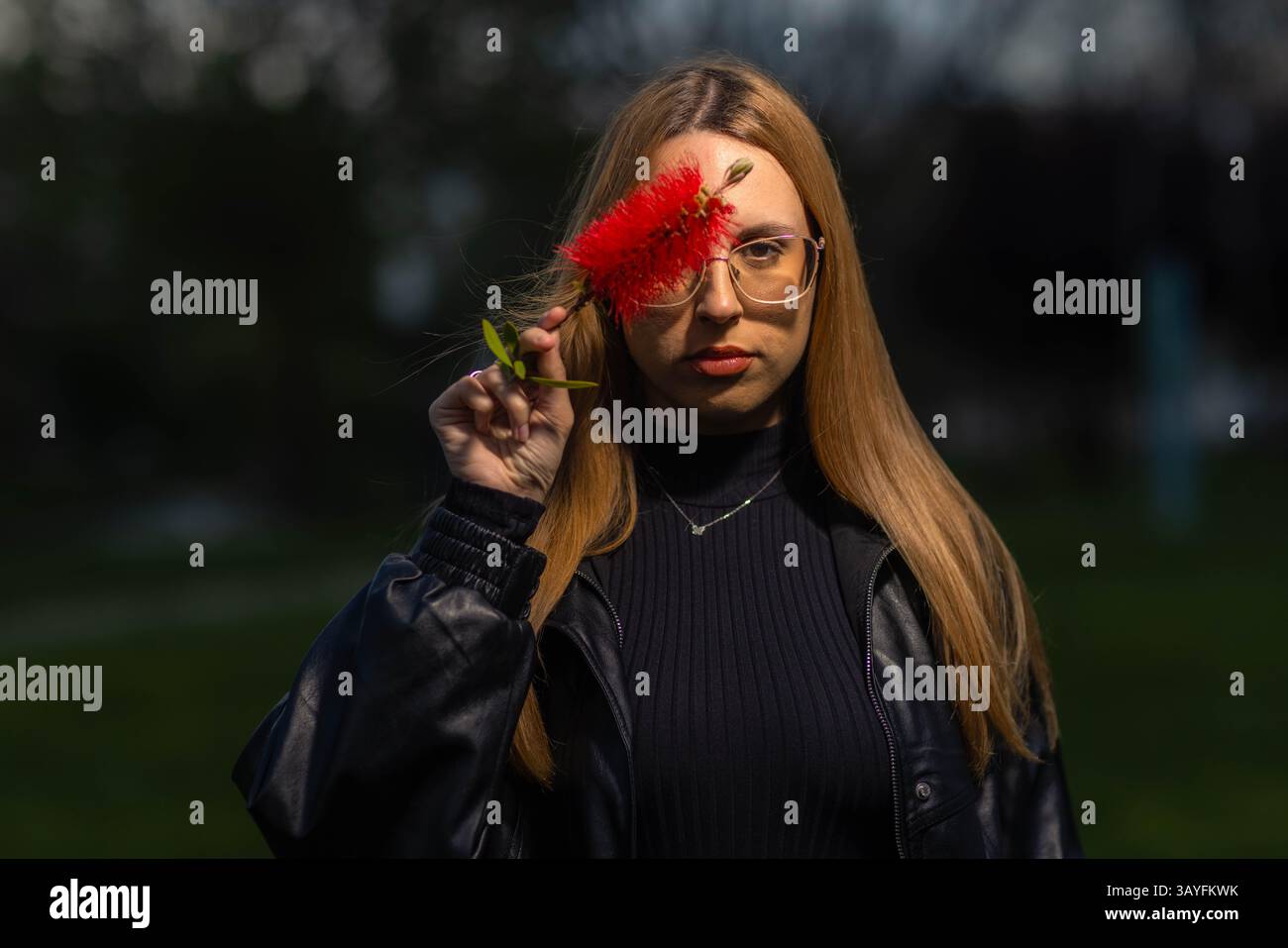Amici alla moda che posano contro un muro di pietra rustico in un lussureggiante ambiente all'aperto Foto Stock