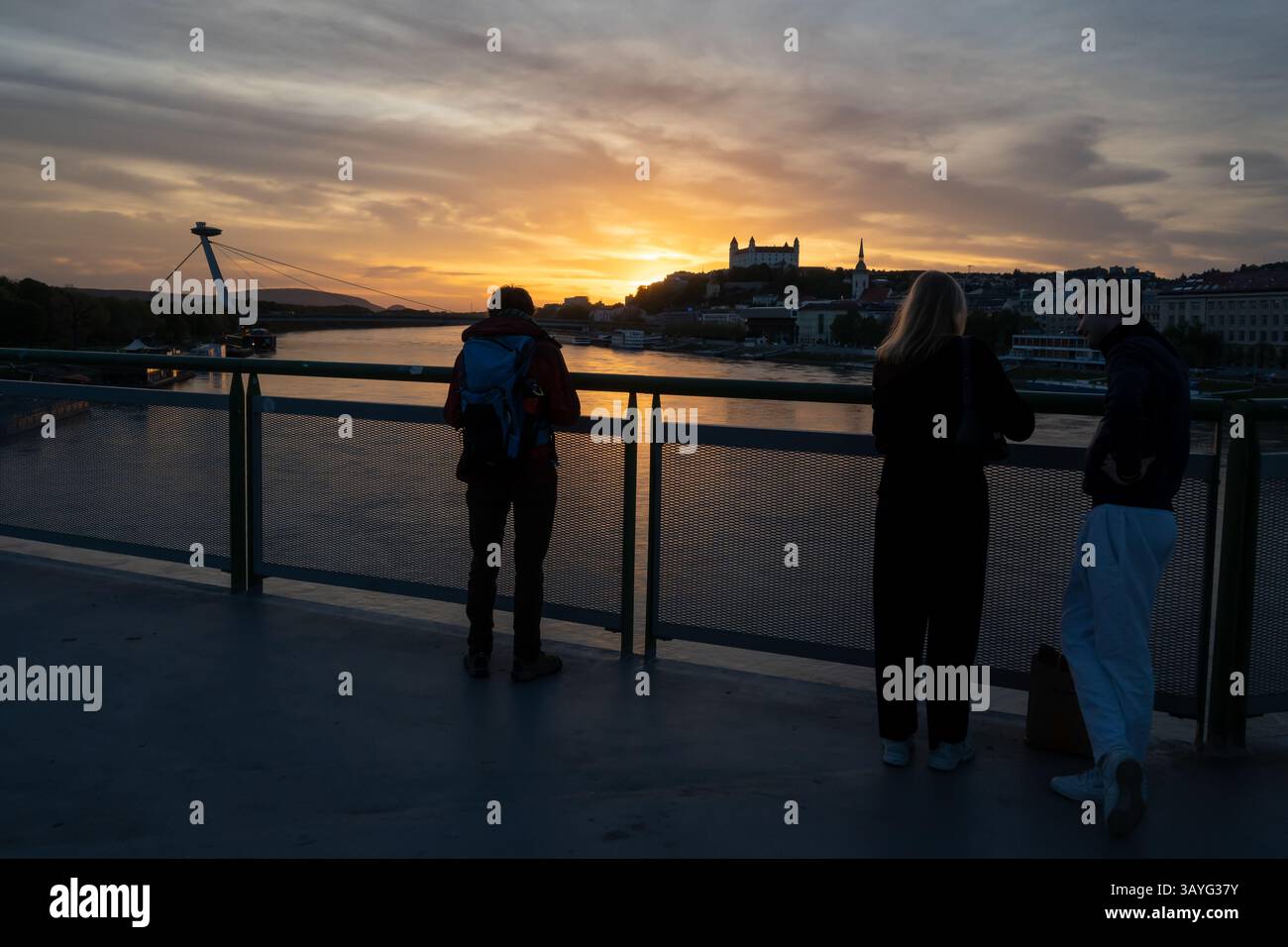 Bratislava, Slovacchia. 20 aprile 2025. La gente osserva il tramonto sul Danubio nella capitale slovacca Bratislava. Sullo sfondo si può ammirare la torre UFO, il ponte SNP, il castello di Bratislava e la cattedrale di San Martino. (Immagine di credito: © Tomas Tkacik/SOPA Images via ZUMA Press Wire) SOLO PER USO EDITORIALE! Non per USO commerciale! Foto Stock