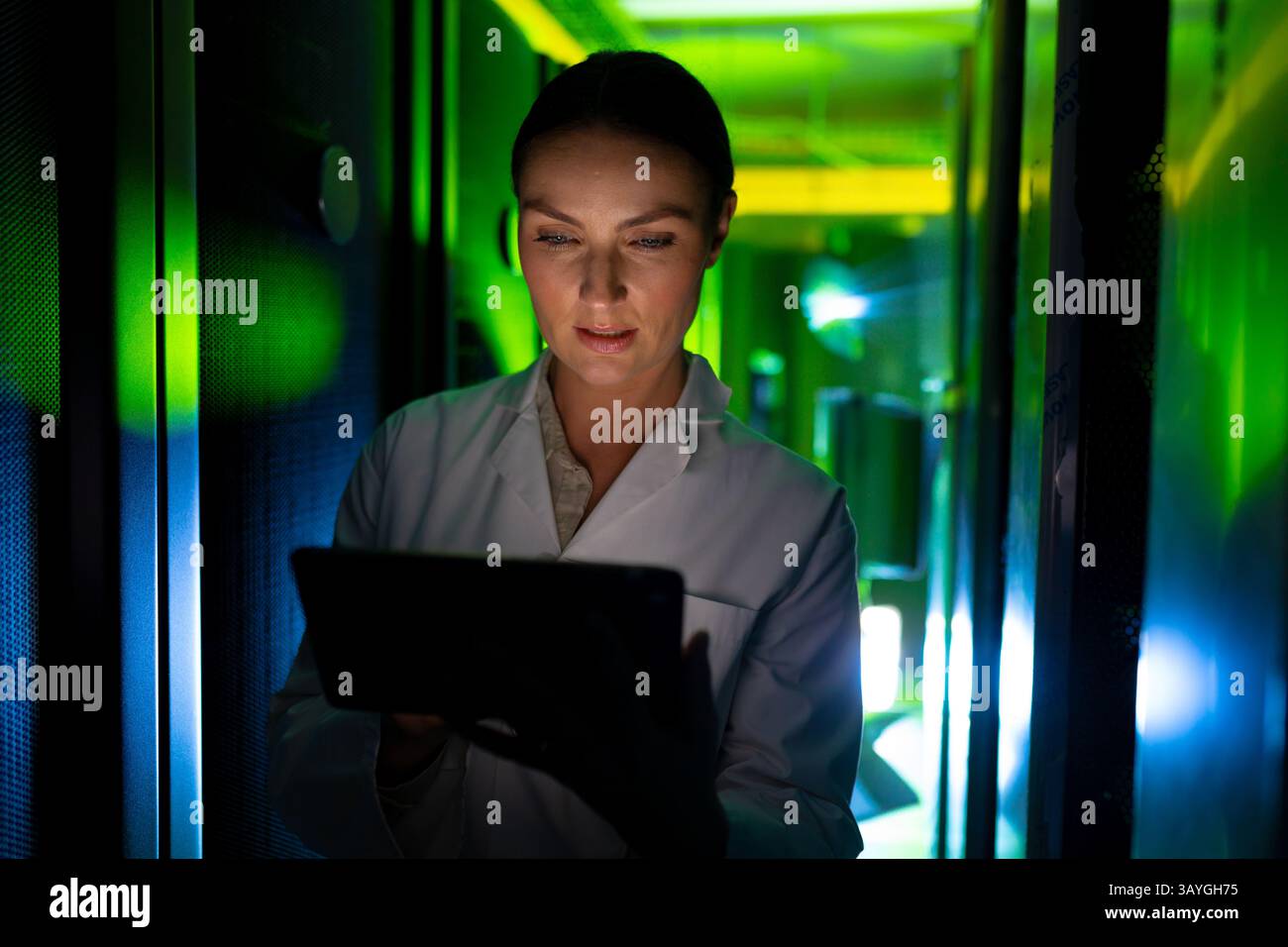 Donna che utilizza un tablet che monitora le luci e i cavi LED nella corsia server del data center, copia spazio Foto Stock