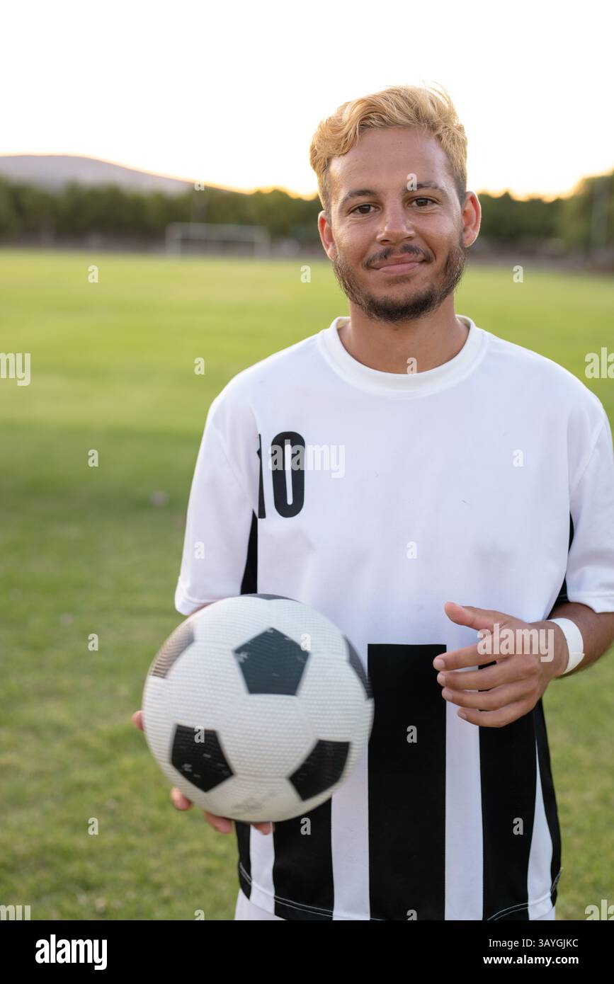 Giovane giocatore di calcio maschile in piedi sul campo di calcio, con palla da calcio e maglia numero dieci Foto Stock