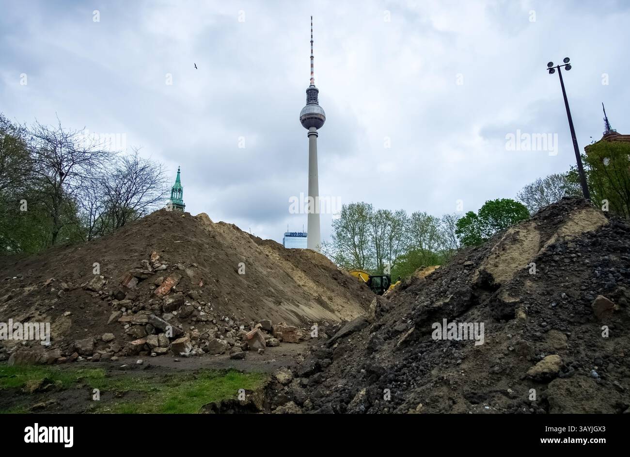 Cantiere con macerie e sporcizia di fronte all'iconica torre della televisione di Berlino, una metafora visiva per il cambiamento permanente di Berlino. Foto Stock