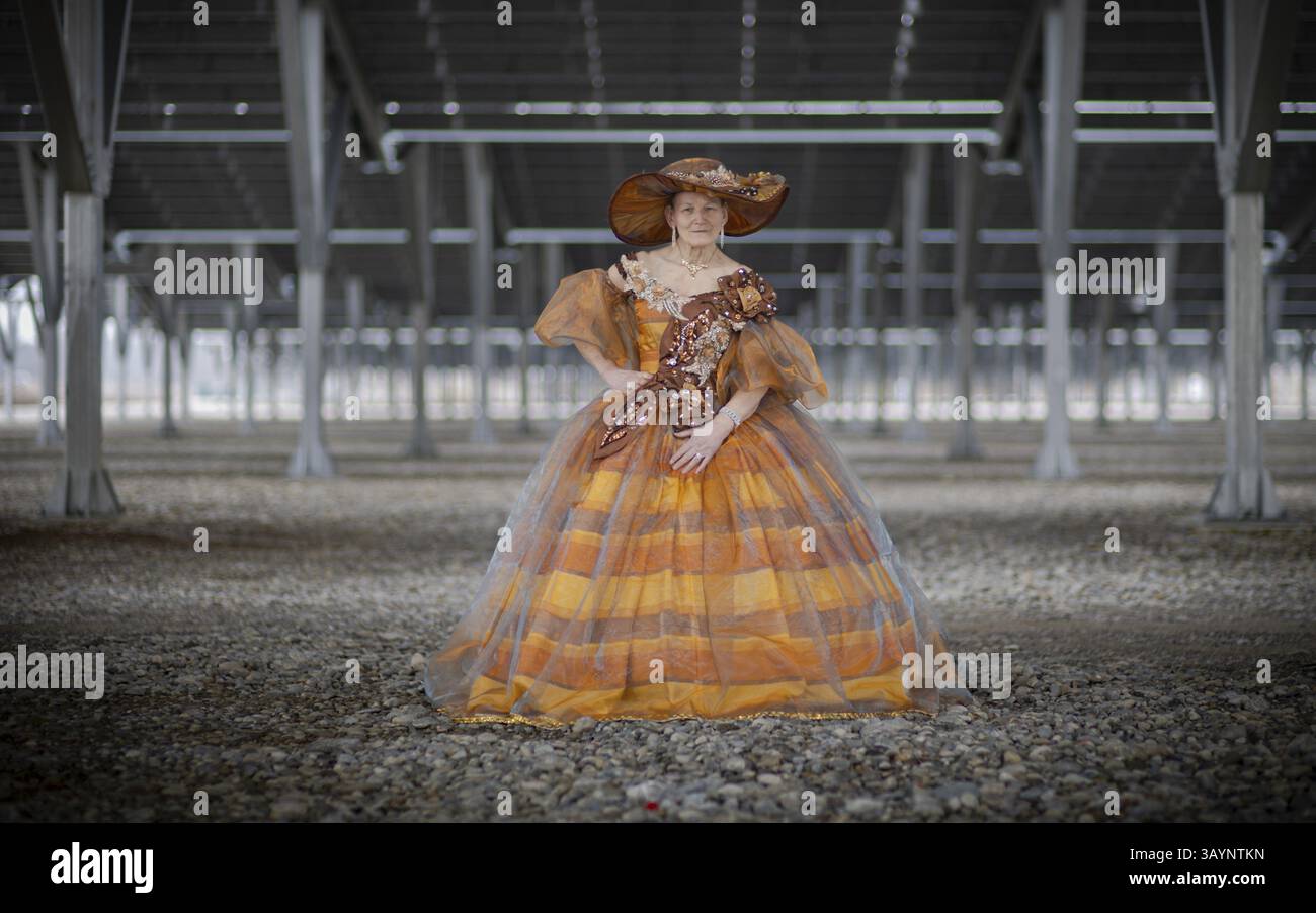 Donna in un abito elaborato si trova in una moderna sala industriale con pavimento in ghiaia, servizio fotografico, Unterallgaeu, Baviera, Germania, Europa Foto Stock