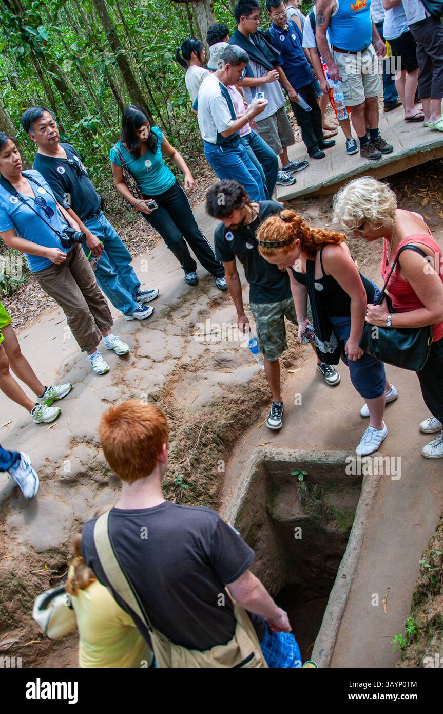 Visitatori dei tunnel di Cu chi che entrano nei tunnel Foto Stock