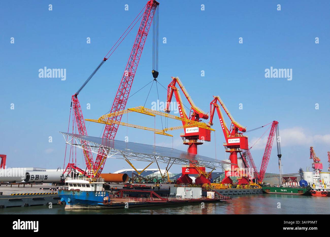 Spedizione di pannelli solari offshore con gru per sollevamento pesante - Renewable Energy Logistics presso il porto Foto Stock