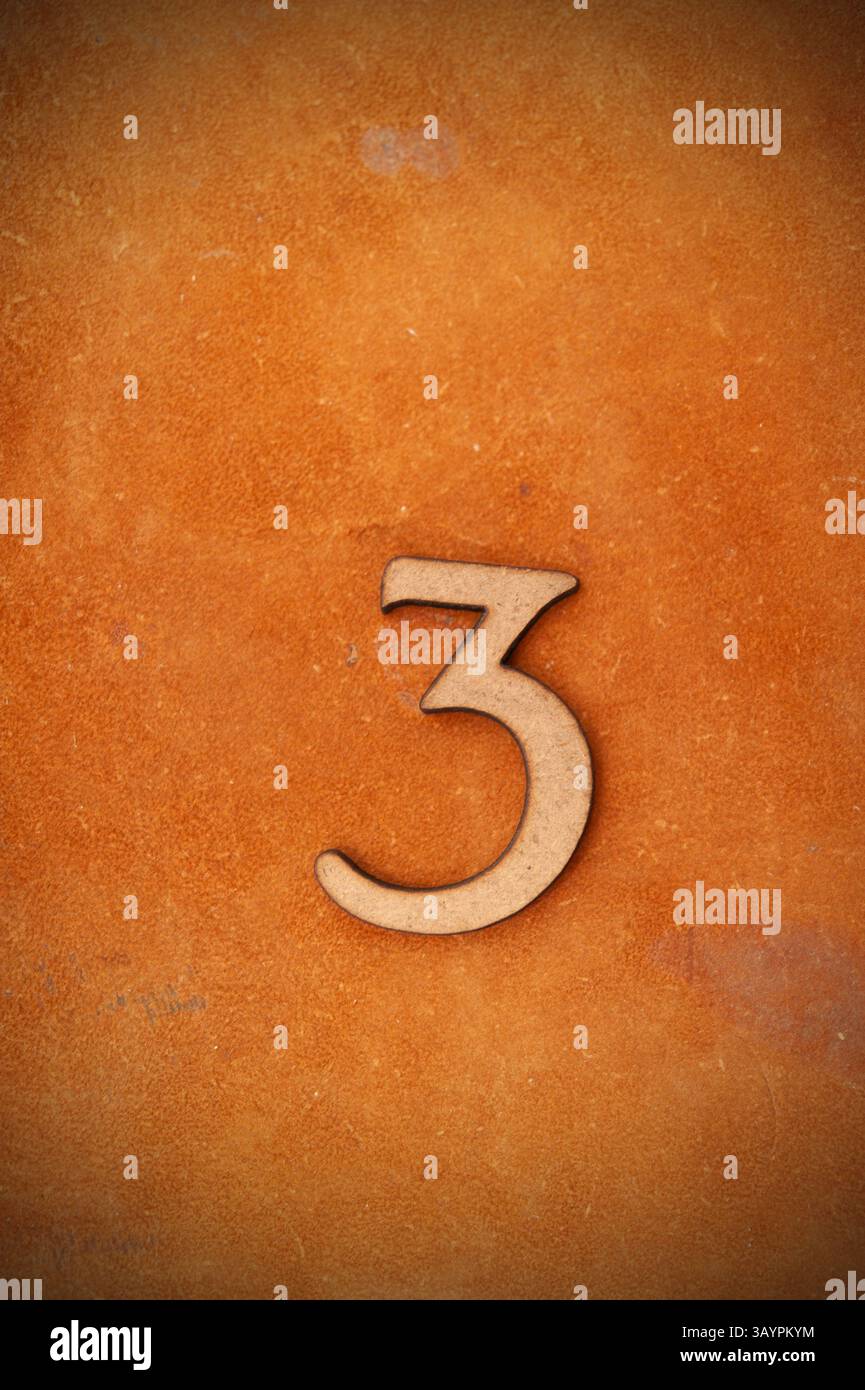 numero tre di legno su sfondo marrone, parte di un insieme di numeri a cifre singole Foto Stock