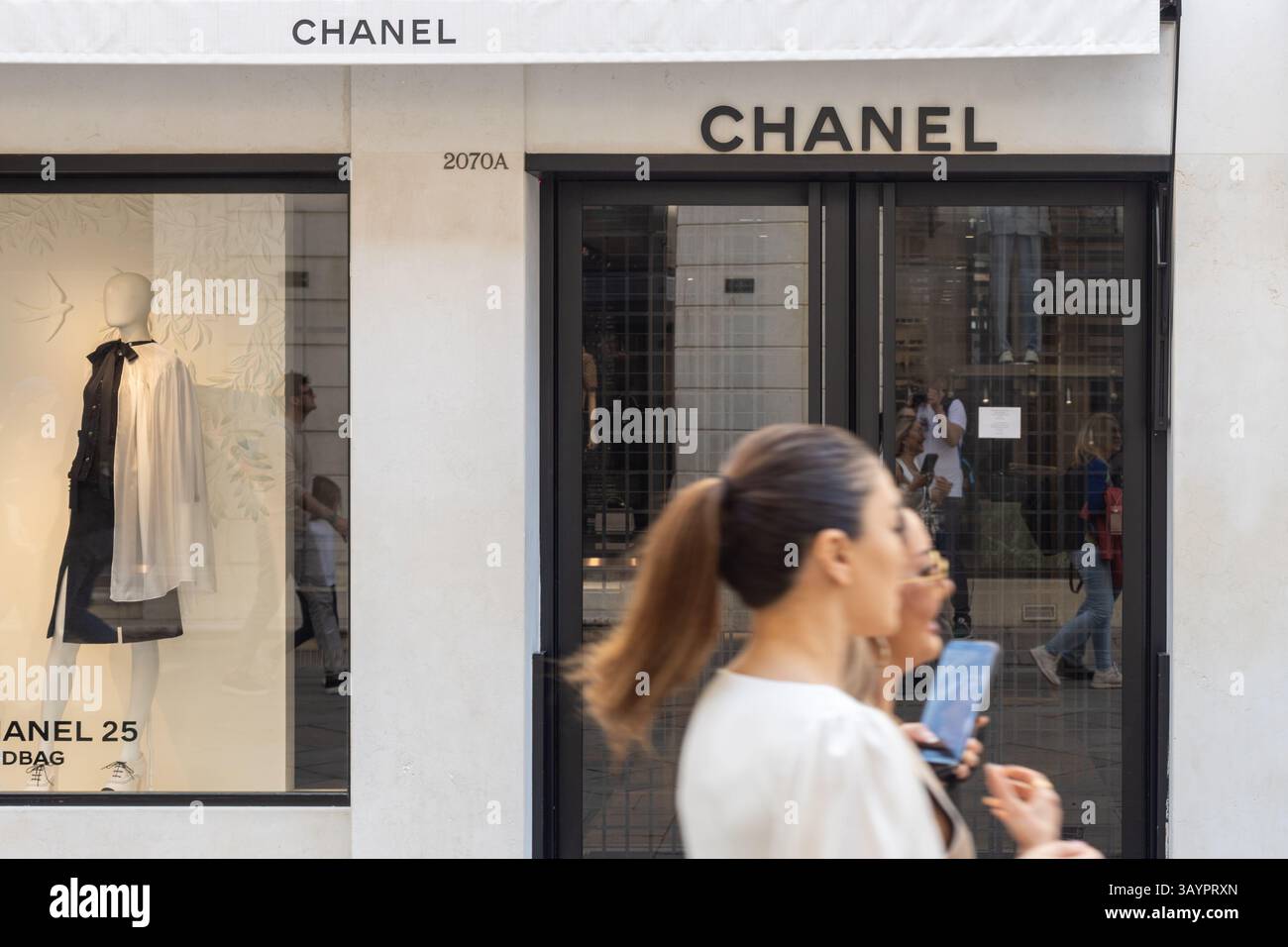 Venezia, Italia - 20 aprile 2025: Logo boutique Chanel e vetrina con gli acquirenti di passaggio a Venezia Foto Stock