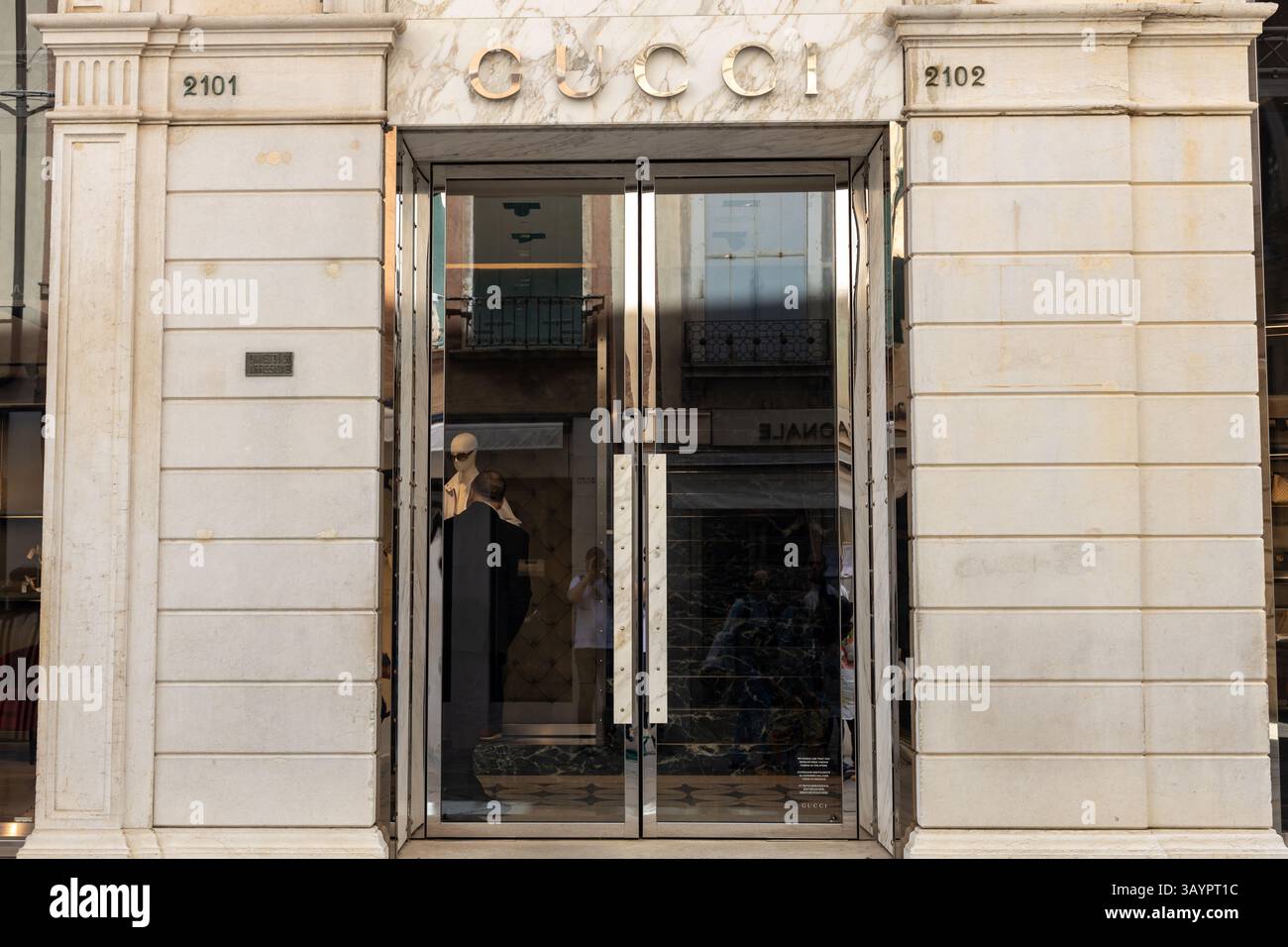 Venezia, Italia - 20 aprile 2025: Ingresso alla boutique Gucci con logo sopra le porte in vetro a specchio Foto Stock