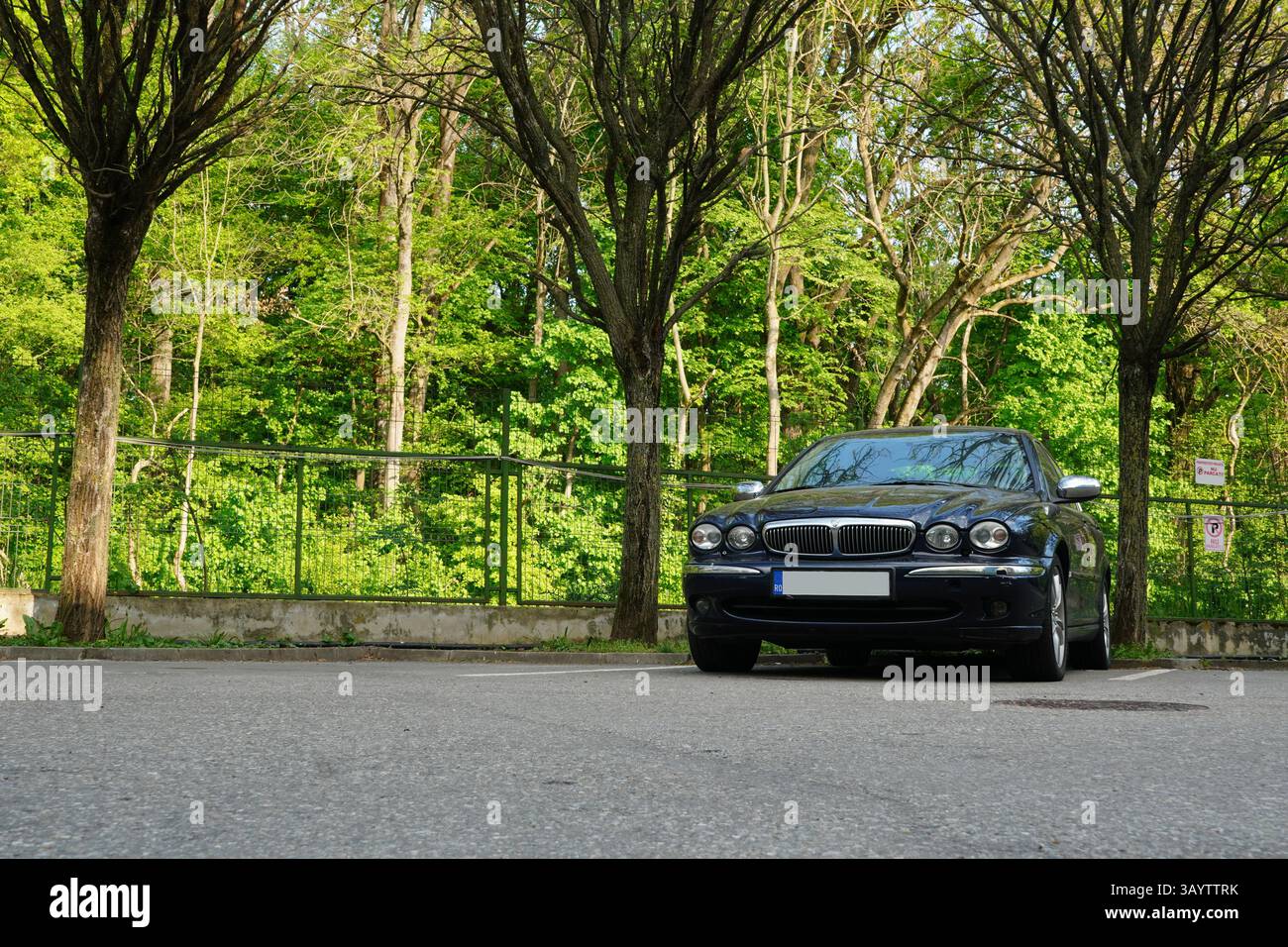 Bucarest, Romania - 21 aprile 2025: Vista frontale dell'auto Jaguar X-TYPE EXECUTIVE 2,2 D Navy nel parcheggio con alberi sullo sfondo Foto Stock