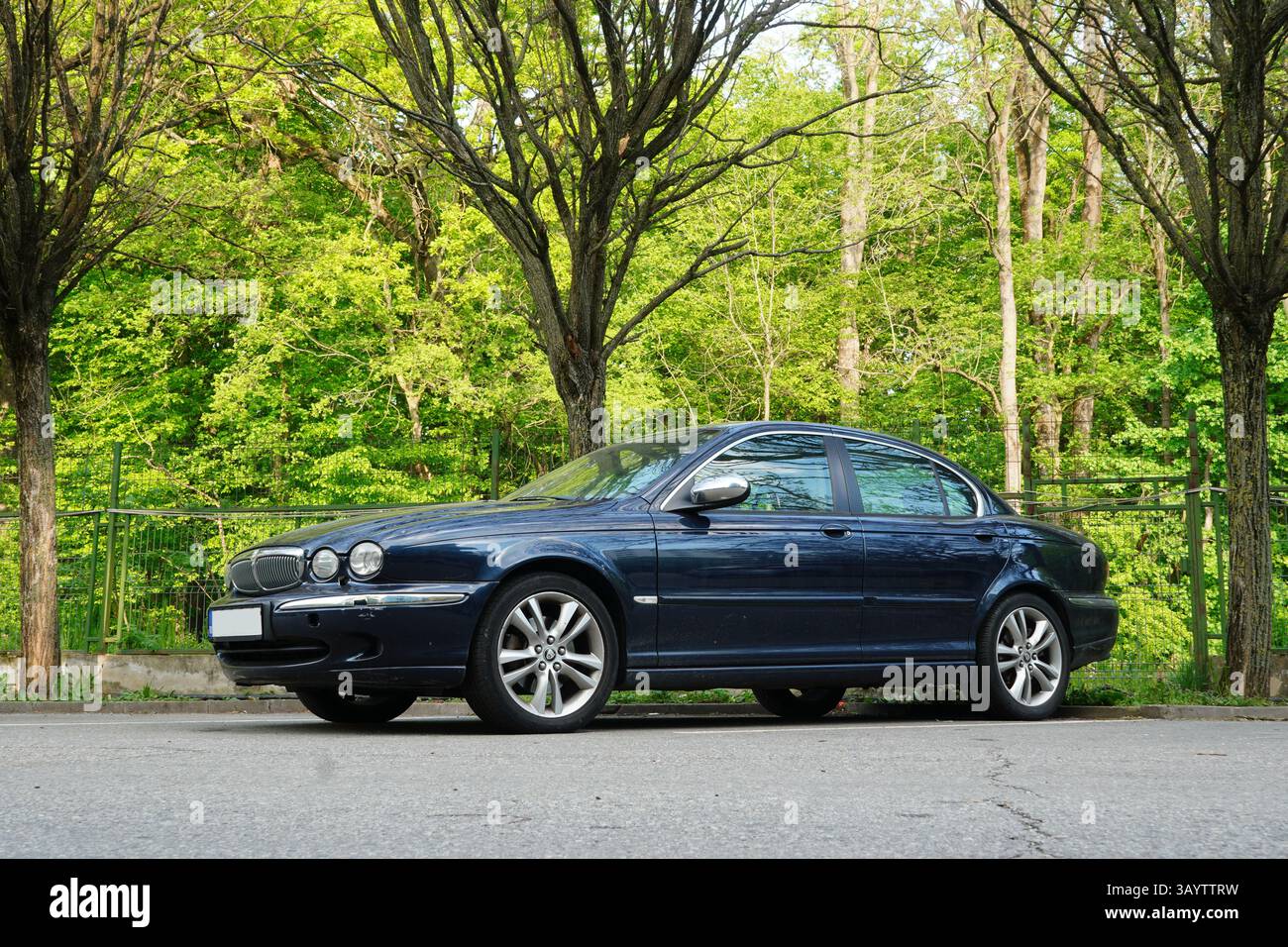 Bucarest, Romania - 21 aprile 2025: Vista laterale della Jaguar X-TYPE EXECUTIVE 2,2 D Navy sul parcheggio con alberi sullo sfondo Foto Stock