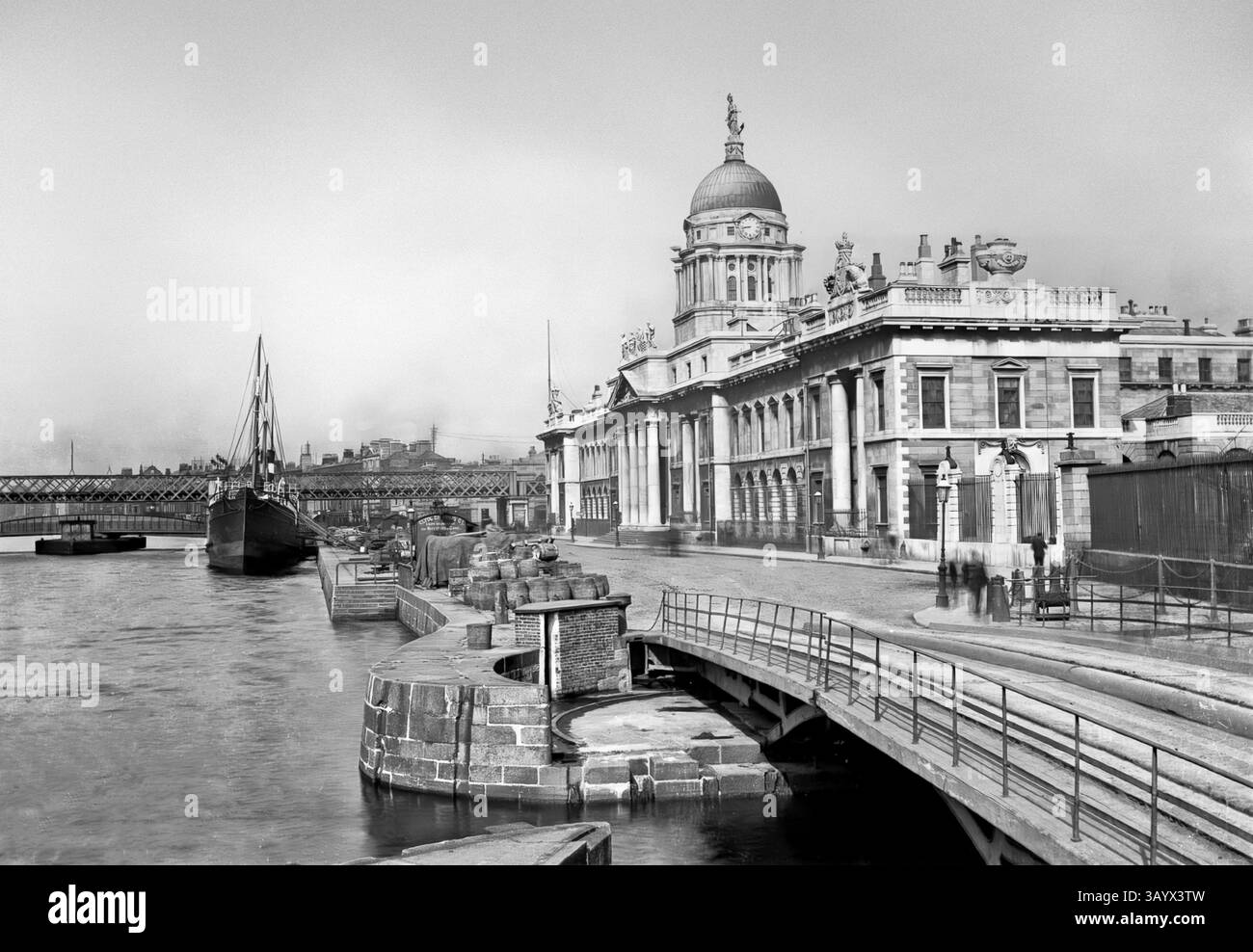 Una vista dei primi anni del XX secolo delle navi ormeggiate accanto alla neoclassica Custom House del XVIII secolo sul fiume Liffey, Dublino, Irlanda. La costruzione iniziò nel 1781 e James Gandon fu nominato architetto, dopo la morte di Thomas Cooley, l'architetto originale del progetto. Una volta completata e aperta, il 7 novembre 1791, la costruzione era costata £ 200.000, una somma considerevole all'epoca. Le quattro facciate dell'edificio sono decorate con stemmi e sculture ornamentali (di Edward Smyth) che rappresentano i fiumi dell'Irlanda. Foto Stock