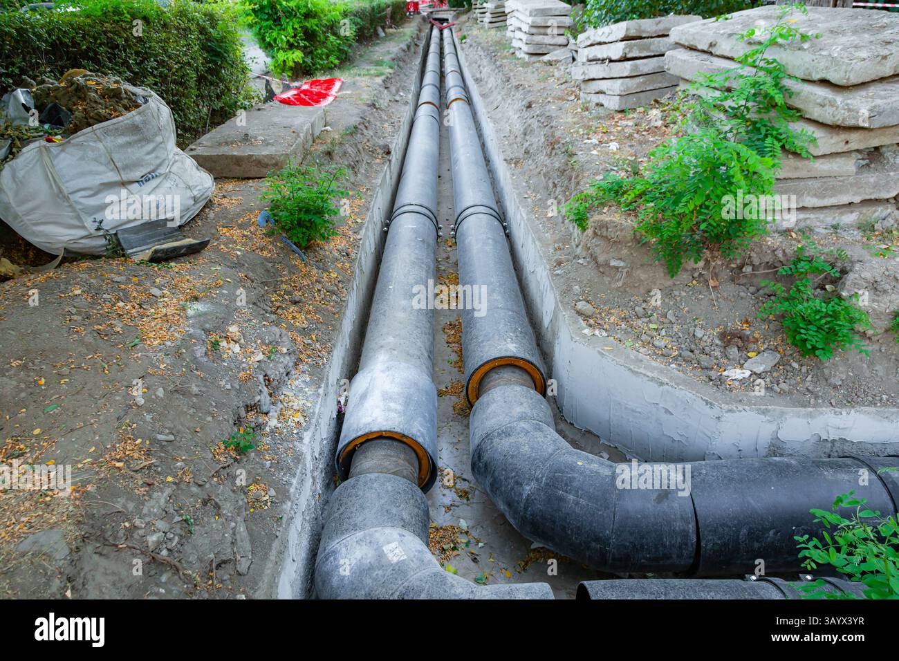 Posa di nuovi tubi dell'acqua di grande diametro nel terreno della città. Foto Stock