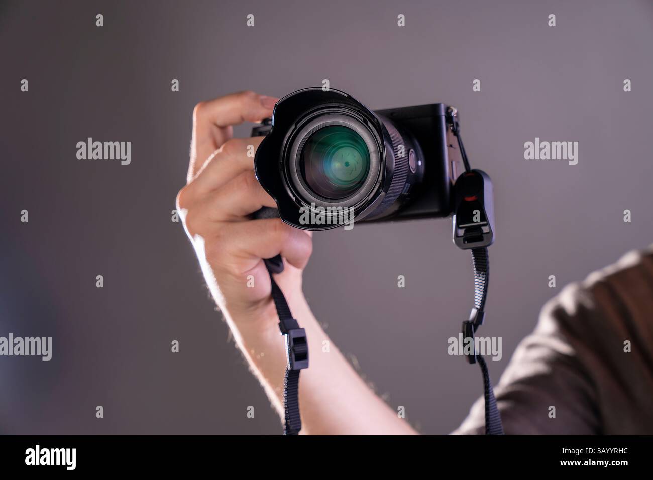 Primo piano della mano di un fotografo con una fotocamera moderna. Concetto di lavoro creativo, fotografia professionale, tecnologia e ispirazione. Perfetto per Foto Stock