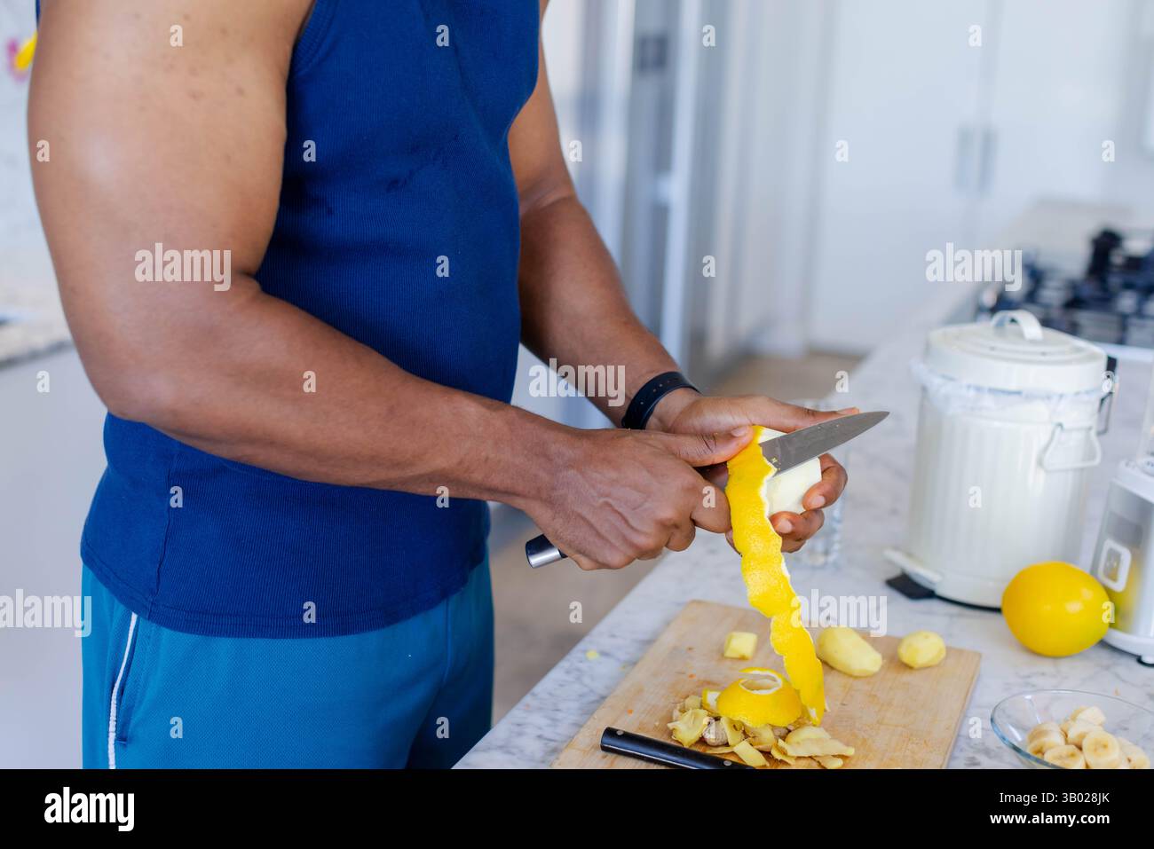 Uomo afro-americano che sbuccia il limone sul piano della cucina, con coltello da cucina, spazio copia Foto Stock
