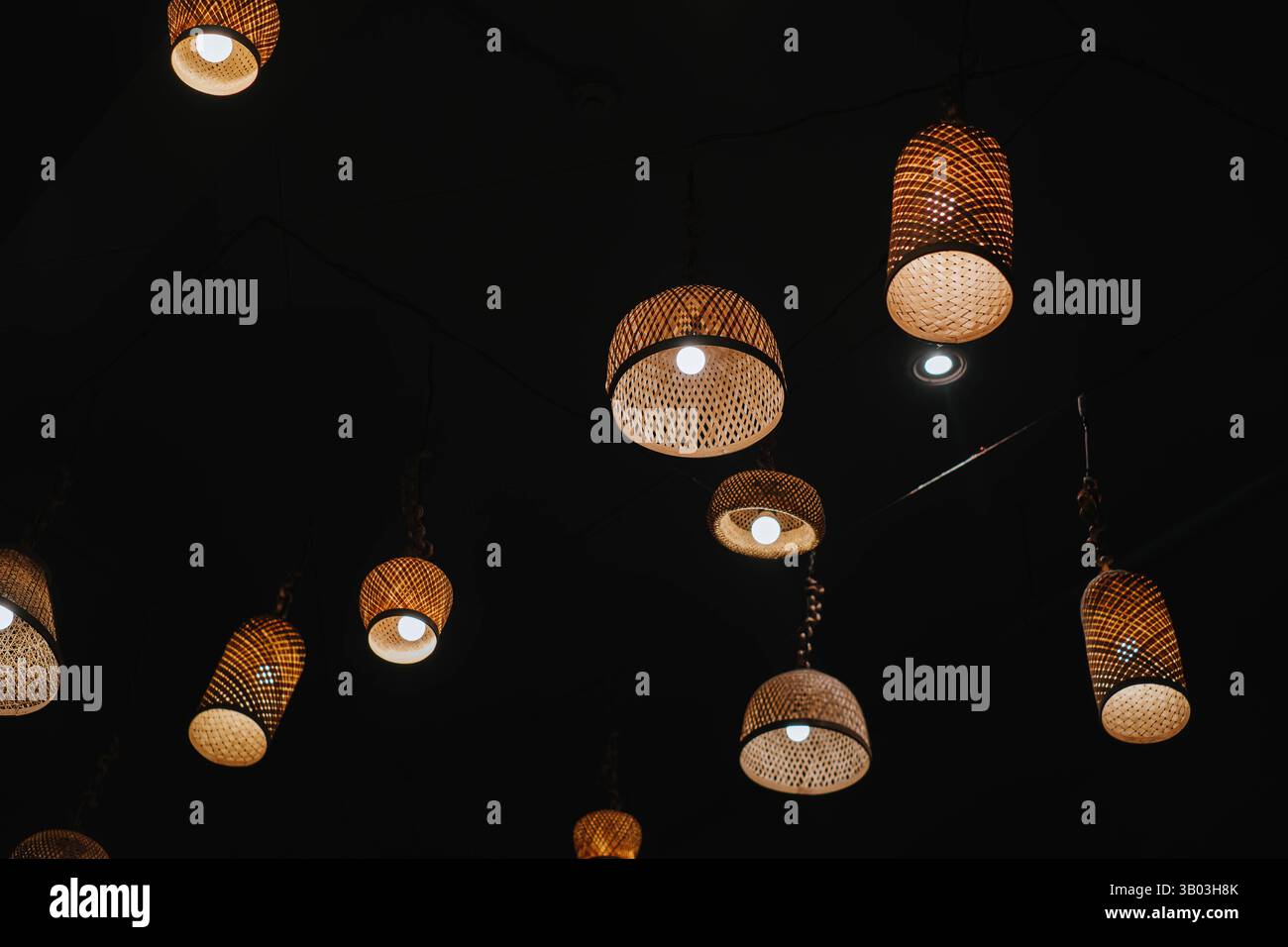 Lampade a sospensione in rattan intrecciato con luci calde e soffitto scuro Foto Stock