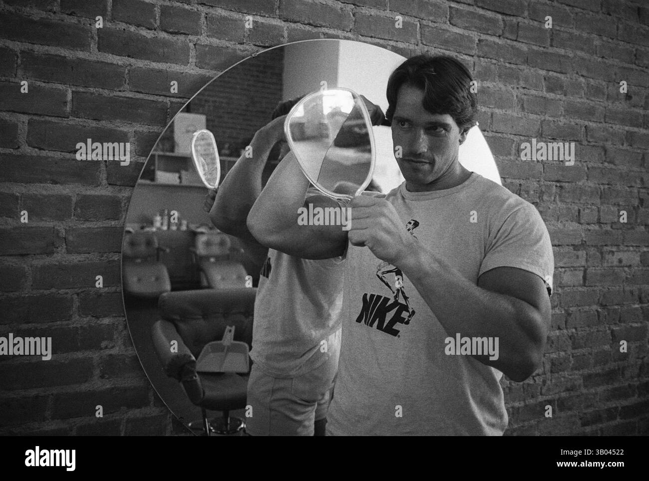 27 marzo 1979 - Los Angeles, CA, USA - il bodybuilder professionista ARNOLD SCHWARZENEGGER si prepara davanti a un grande specchio mentre tiene in mano uno specchio. Nato in un piccolo villaggio in Austria, Arnold iniziò ad allenarsi con i pesi in giovane età e presto raggiunse la vetta come campione di bodybuilding. La sua pausa nella recitazione è arrivata nel film di successo del 1982 "Conan the Barbarian". Da Conan, Arnold ha mantenuto una lunga carriera come attore. Arnold divenne anche attivo nella politica degli Stati Uniti all'inizio degli anni '80 e da allora è stato votato come governatore della California per mezzo di un controverso richiamo dell'ex G Foto Stock