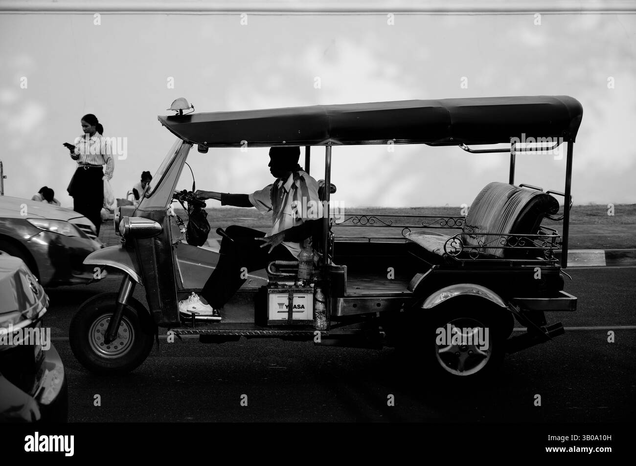 L'autista di tuk-tuk si ferma all'ombra del tardo pomeriggio vicino alle mura del Grand Palace Foto Stock