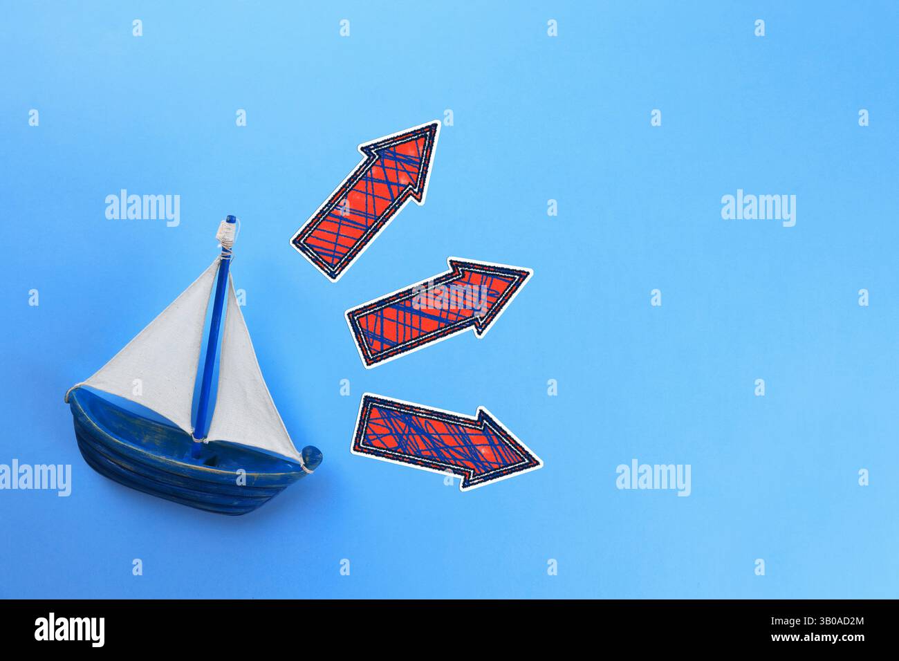 Guida. Frecce che puntano in direzioni diverse davanti alla nave giocattolo su sfondo blu, vista dall'alto Foto Stock