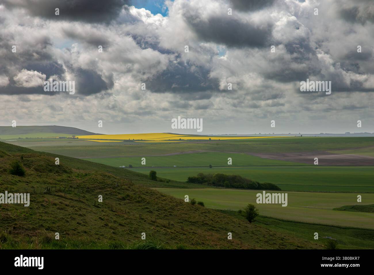 Vista panoramica di un vasto paesaggio di campagna con colline ondulate, campi verdi e un cielo nuvoloso spettacolare. Cherhill, Wiltshire Foto Stock