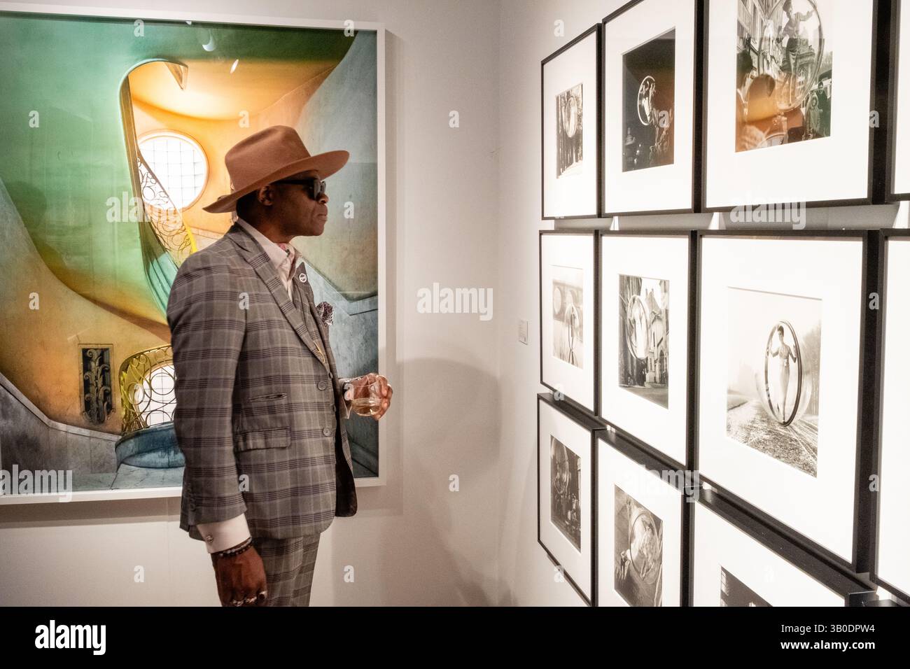 New York, New York, Stati Uniti. 23 aprile 2025. Il Photography Show, sponsorizzato dalla Association of International Photography Art Dealers (AIPAD), è stato inaugurato presso il Park Avenue Armory. Un partecipante accanito allo stand di Holden Kuntz, con le foto di Melvyn Sokolsky sulla destra e una grande stampa di Michael Eastman. Crediti: Ed Lefkowicz/Alamy Live News Foto Stock