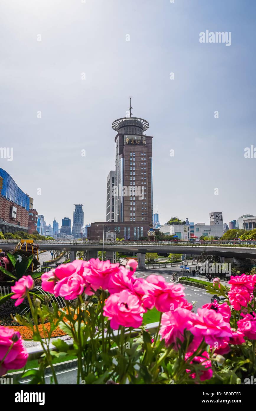Shanghai, Cina - 1° aprile 2025: Vivaci fiori rosa fanno da cornice al centro espositivo di pianificazione urbana di Shanghai con il suo iconico osservatorio circolare sul tetto, Foto Stock